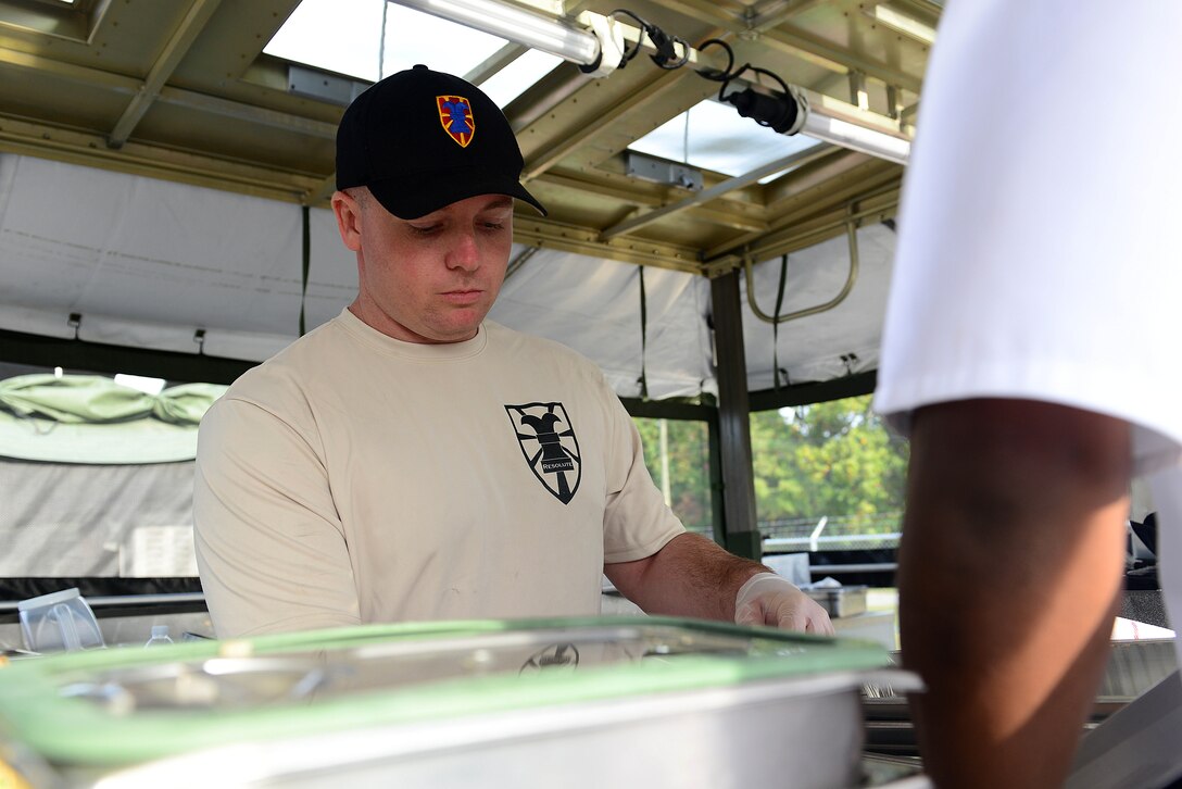 U.S. Army Sgt. John Edwards, 149th Seaport Operation Company, 11th Transportation Battalion, 7th Transportation Brigade (Expeditionary) food service specialist, assists a teammate during the two-day Iron Chef competition hosted by the brigade at Fort Eustis, Va., Oct. 29, 2014. Edwards was part of a four-man team in the competition which included a ruck march, written test, board meeting and a culinary competency test. (U.S. Air Force photo by Airman 1st Class Kimberly Nagle/Released)