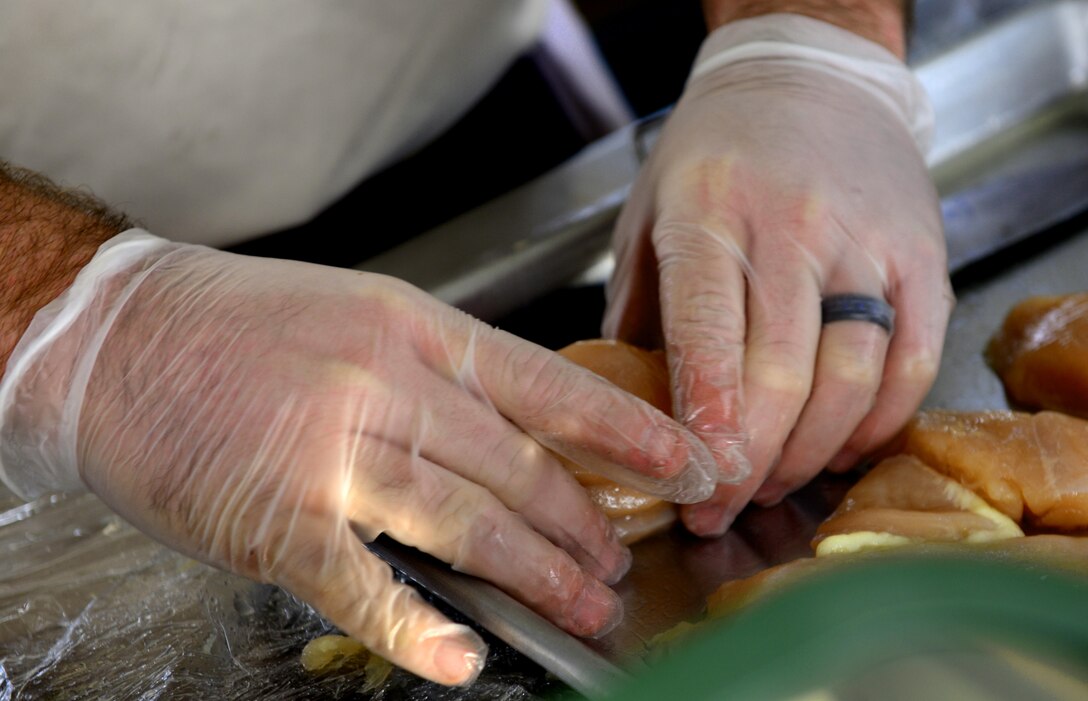 A U.S. Army Soldier assigned to the 7th Transportation Brigade (Expeditionary) prepares chicken for the two–day Iron Chef competition at Fort Eustis, Va., Oct. 29, 2014. During the competition, four-man teams of Soldiers produced an appetizer, entree and dessert. (U.S. Air Force photo by Airman 1st Class Kimberly Nagle/Released)
