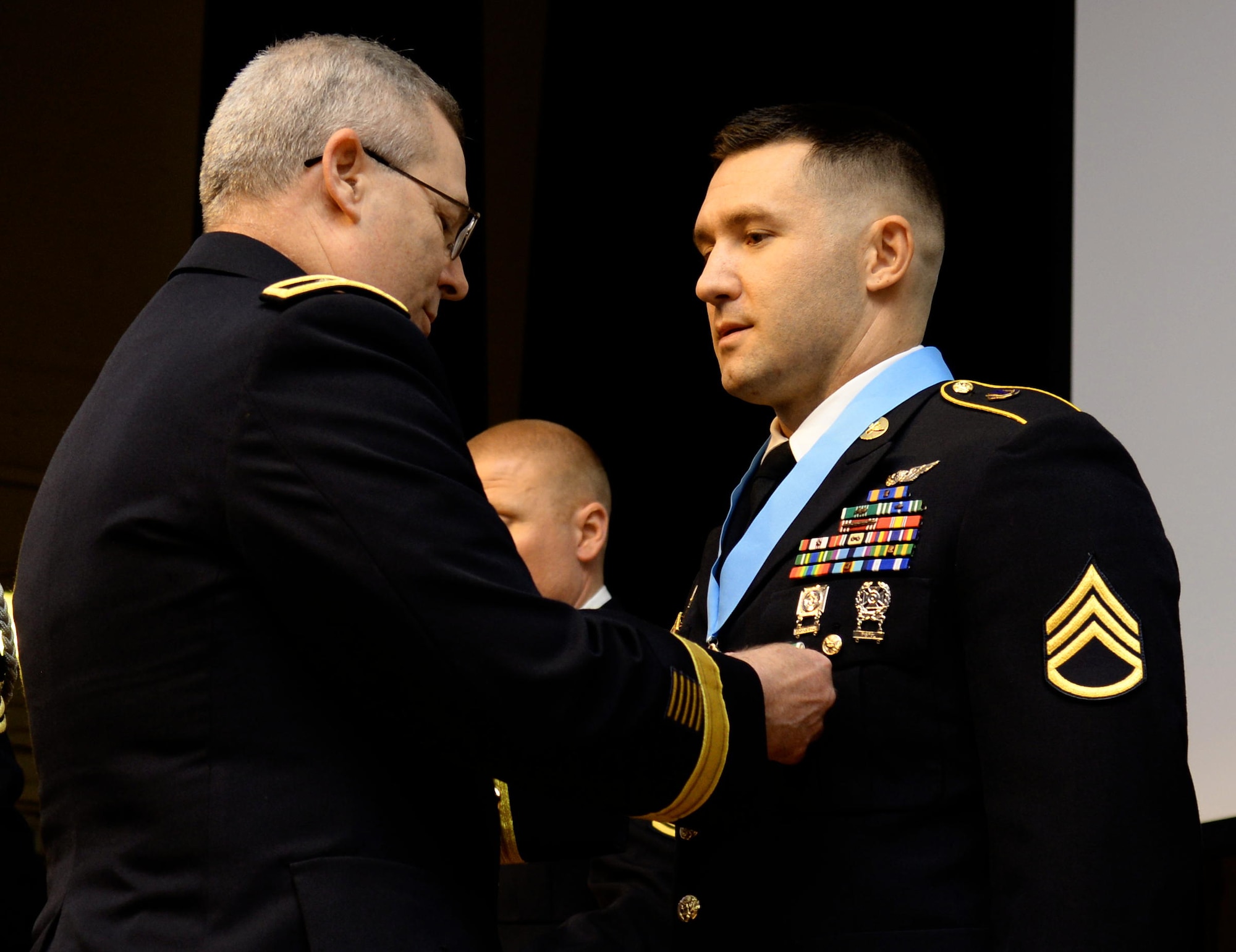 U.S. Army Maj. Gen. Ross E. Ridge, Training and Doctrine Command Initial Military Training deputy commanding general, presents Staff Sgt. Thomas Featsent, 128th Aviation Brigade rotary wing instructor, a Sergeant Audie Murphy Club medallion and an Army Commendation Medal during a SAMC induction ceremony at Fort Eustis, Va., Oct. 29, 2014. Club members dedicate themselves to living to the high standard of Sgt. Audie Murphy, one of the most highly dedicated Soldiers in the Army's history for his heroic efforts in combat during World War II. (U.S. Air Force photo by Senior Airman Austin Harvill/Released)