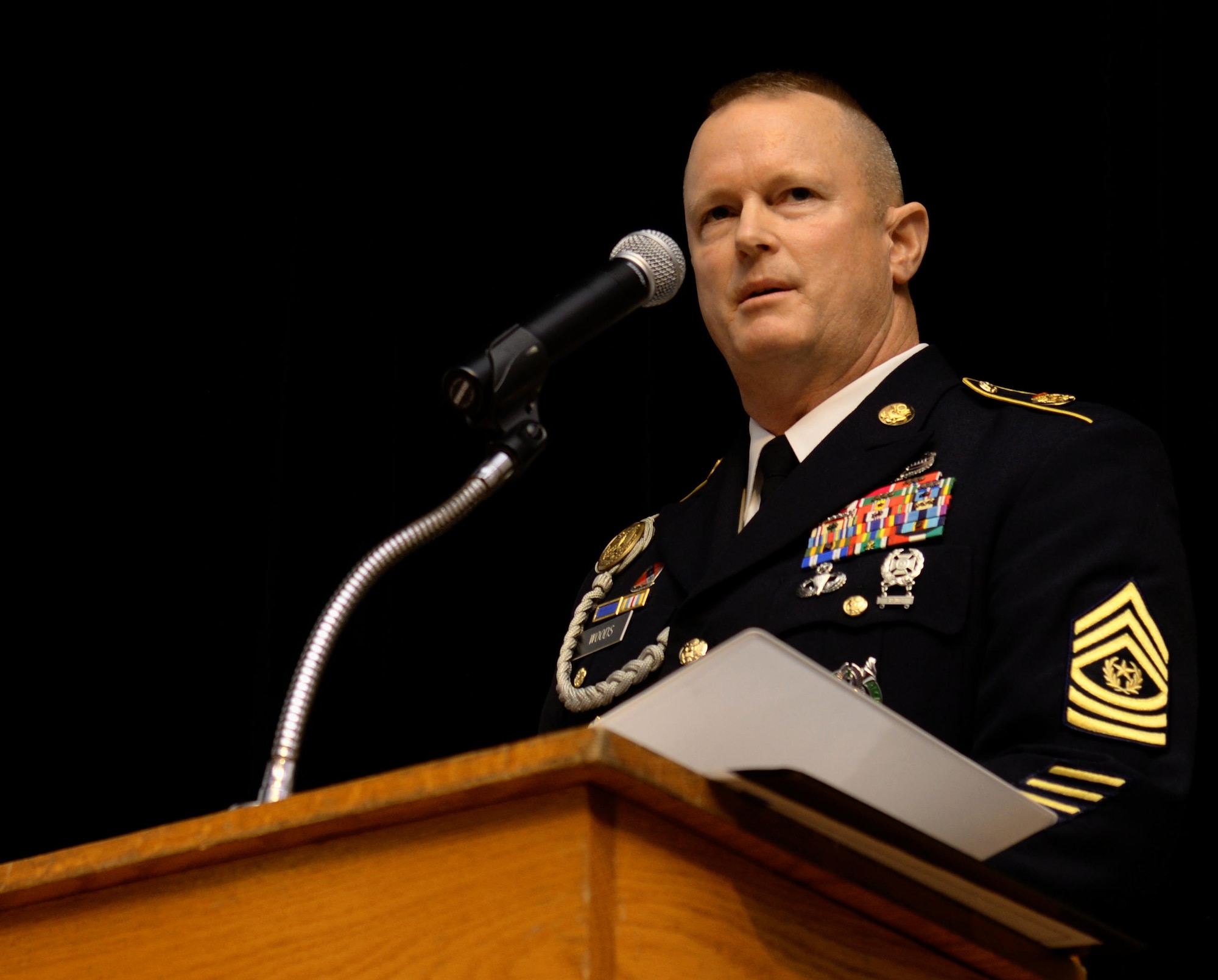U.S. Army Command Sgt. Maj. Dennis J. Woods, Training and Doctrine Command Initial Military Training command sergeant major, speaks during a Sergeant Audie Murphy Club induction ceremony at Fort Eustis, Va., Oct. 29, 2014. During the ceremony, attendees watched a reenactment of one of Murphy's heroic actions, where he fought atop a damaged tank after calling in artillery strikes near his position. (U.S. Air Force photo by Senior Airman Austin Harvill/Released)