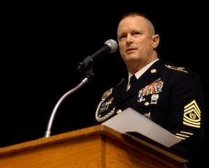 U.S. Army Command Sgt. Maj. Dennis J. Woods, Training and Doctrine Command Initial Military Training command sergeant major, speaks during a Sergeant Audie Murphy Club induction ceremony at Fort Eustis, Va., Oct. 29, 2014. During the ceremony, attendees watched a reenactment of one of Murphy's heroic actions, where he fought atop a damaged tank after calling in artillery strikes near his position. (U.S. Air Force photo by Senior Airman Austin Harvill/Released)