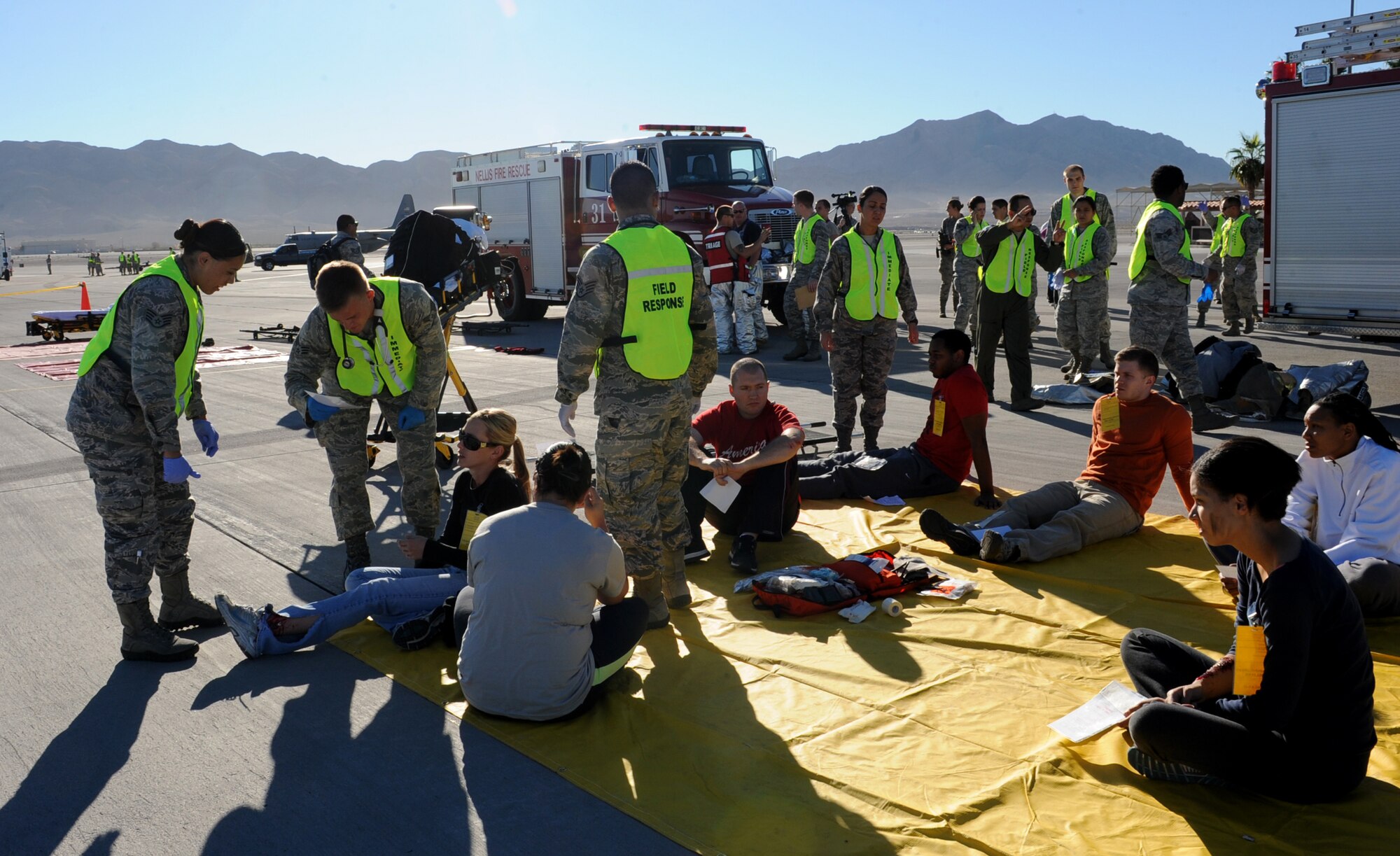 Emergency medical technicians asses a simulated casualty during the major accident response exercise at Nellis Air Force Base, Nev., Oct. 28, 2014. The simulated wounded were separated into three categories based on severity of injury in order to treat those with the most life-threatening injuries first. (U.S. Air Force photo by Staff Sgt. Victoria Sneed)