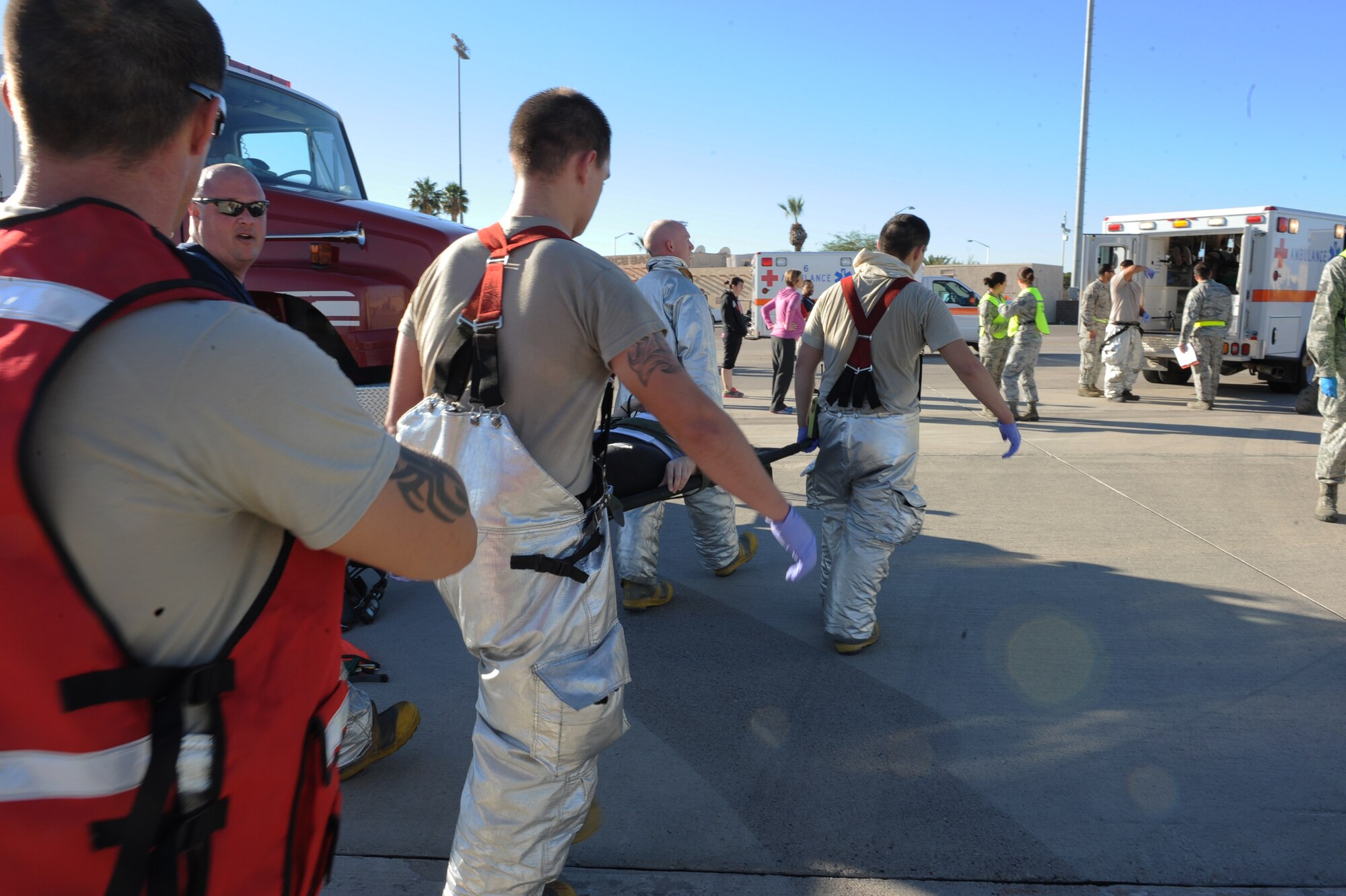 Firemen from the 99th Civil Engineer Squadron carry a simulated casualty to an ambulance for transport during the major accident response exercise at Nellis Air Force Base, Nev., Oct. 28, 2014. Large-scale exercises allow base agencies to test partnerships to ensure cooperation and seamless transitions from one agency to another, should an emergency occur on base. (U.S. Air Force photo by Staff Sgt. Victoria Sneed)