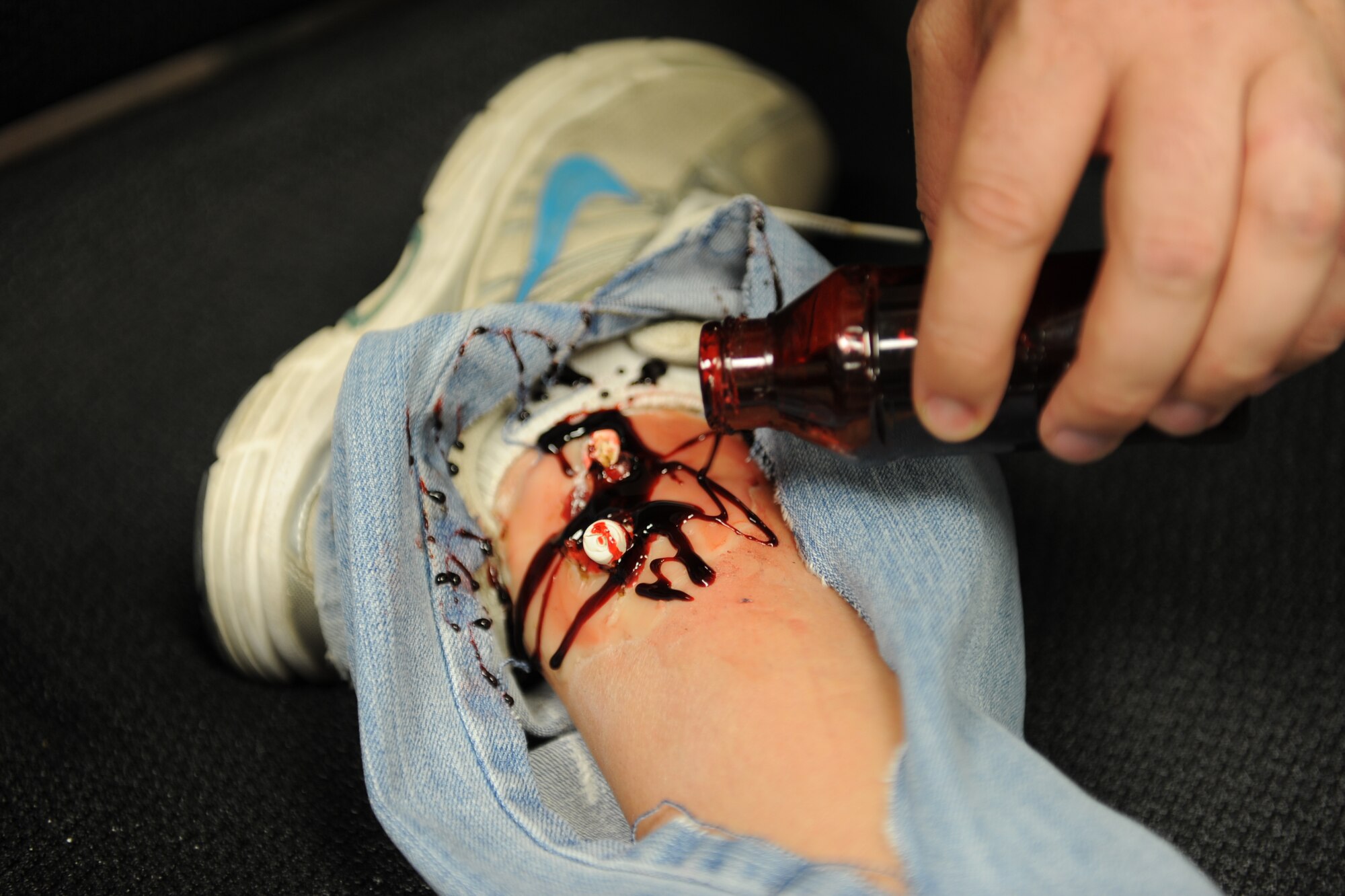 Staff Sgt. Michael Zumbrunn, 99th Medical Support Squadron medical readiness craftsman, pours fake blood on a simulated protruding bone in preparation for the major accident response exercise at Nellis Air Force Base, Nev., Oct. 28, 2014. Wounds are created by medical group personnel for first responders to triage, treat and transport from the scene of a simulated accident. (U.S. Air Force photo by Staff Sgt. Victoria Sneed)