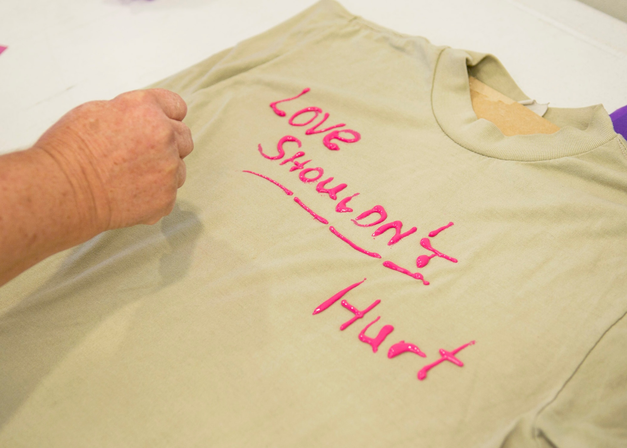 A volunteer writes a message on a t-shirt that will be displayed during domestic violence awareness month Oct. 21 on Tyndall AFB, Fla. The t-shirt display is used to raise awareness of domestic violence. (U.S. Air Force photo by Airman 1st Class Ty-Rico Lea)