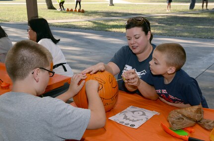 Cindy Vigneron and her sons, Nicholas and Nathan, carve a pumpkin during the Halloween-themed “Hearts Apart” event Oct. 27 at Joint Base San Antonio-Randolph’s Eberle Park. The Hearts Apart program offered by the Military and Family Readiness Centers supports spouses and children experiencing separation due to deployment, remote assignment or extended TDY. The program provides families with social activities that allow them to come together, build friendships and ease the strain of separation from their loved ones. (U.S. Air Force photo by Johnny Saldivar)