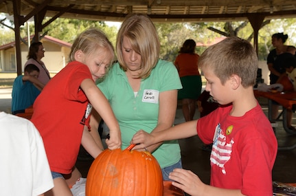Heidi Carroll and her children, Cameron and Kayla, prepare a pumpkin for carving during the Halloween-themed “Hearts Apart” event Oct. 27 at Joint Base San Antonio-Randolph’s Eberle Park. The Hearts Apart program offered by the Military and Family Readiness Centers supports spouses and children experiencing separation due to deployment, remote assignment or extended TDY. The program provides these families with social activities that allow them to come together, build friendships and ease the strain of separation from their loved ones. (U.S. Air Force photo by Johnny Saldivar)