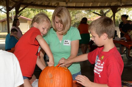 Heidi Carroll and her children, Cameron and Kayla, prepare a pumpkin for carving during the Halloween-themed “Hearts Apart” event Oct. 27 at Joint Base San Antonio-Randolph’s Eberle Park. The Hearts Apart program offered by the Military and Family Readiness Centers supports spouses and children experiencing separation due to deployment, remote assignment or extended TDY. The program provides these families with social activities that allow them to come together, build friendships and ease the strain of separation from their loved ones. (U.S. Air Force photo by Johnny Saldivar)