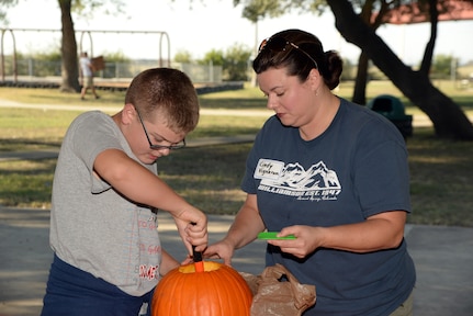 Cindy Vigneron and her son, Nathan, carve a pumpkin during the Halloween-themed “Hearts Apart” event Oct. 27 at Joint Base San Antonio-Randolph’s Eberle Park. The Hearts Apart program offered by the Military and Family Readiness Centers supports spouses and children experiencing separation due to deployment, remote assignment or extended TDY. The program provides these families with social activities that allow them to come together, build friendships and ease the strain of separation from their loved ones. (U.S. Air Force photo by Johnny Saldivar)