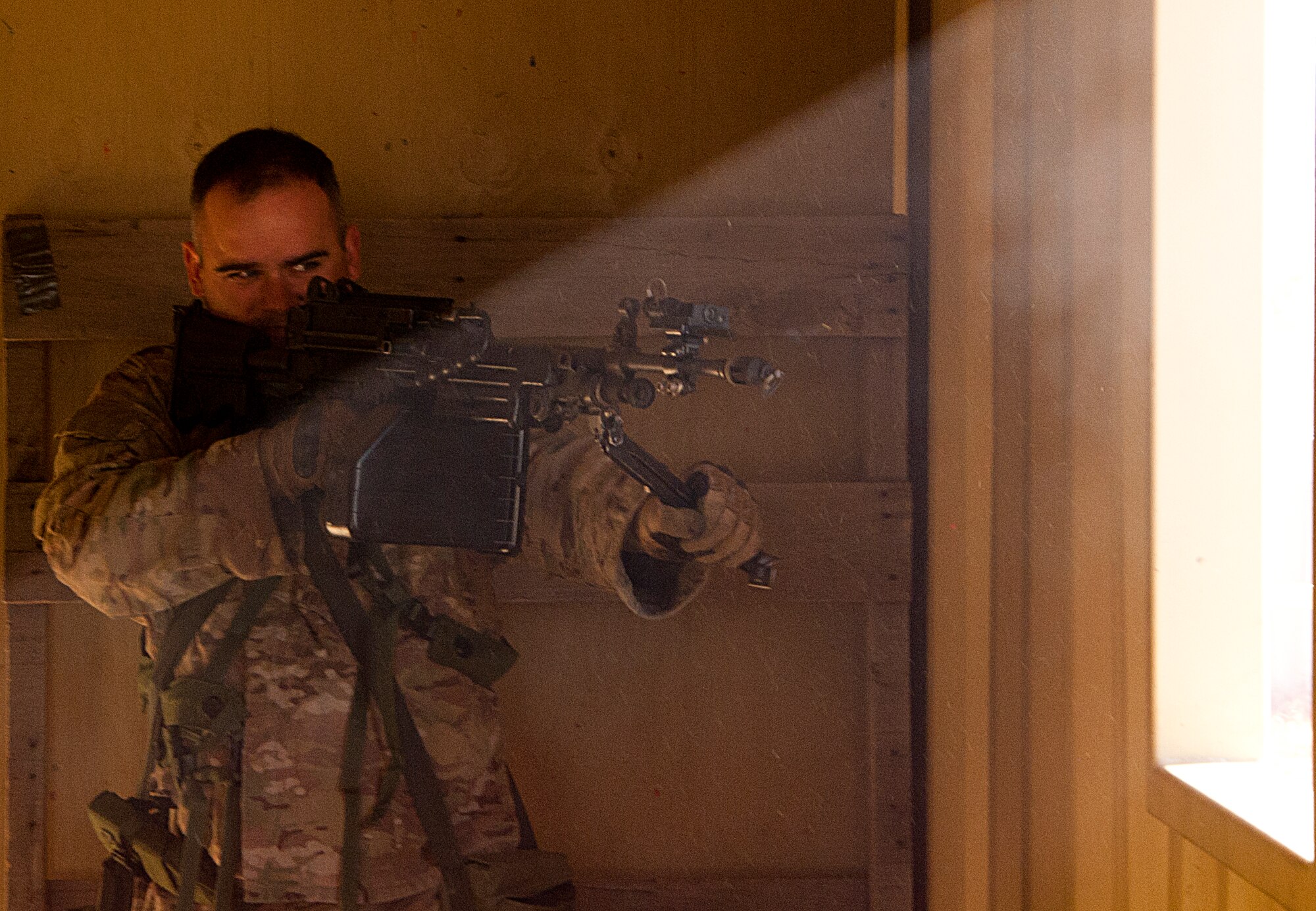 Staff Sgt. Christopher McAleer, 620th Ground Combat Training Squadron formal training instructor, armed with an M-249 loaded with blank rounds, looks through a window during a training exercise at Camp Guernsey, Wyo., Oct. 17, 2014. McAleer and other 620th GCTS training instructors played opposing-force gunmen in training exercises during the Nuclear Convoy Course. (U.S. Air Force photo by Senior Airman Jason Wiese)