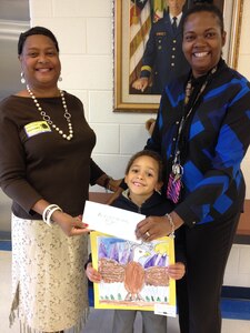 Arneda Powell, Blacks in Government (BIG) Hampton Roads EBONACT (HRE) chapter president, presents a check Calvin, General Stanford Elementary School student, and Valencia Gross, General Stanford Elementary School art teacher, at General Stanford Elementary School on Fort Eustis, Va., Oct. 20, 2014. The BIG chapter gifted the school’s art department $200 to assist with the sustainment of the art program. (Courtesy photo)