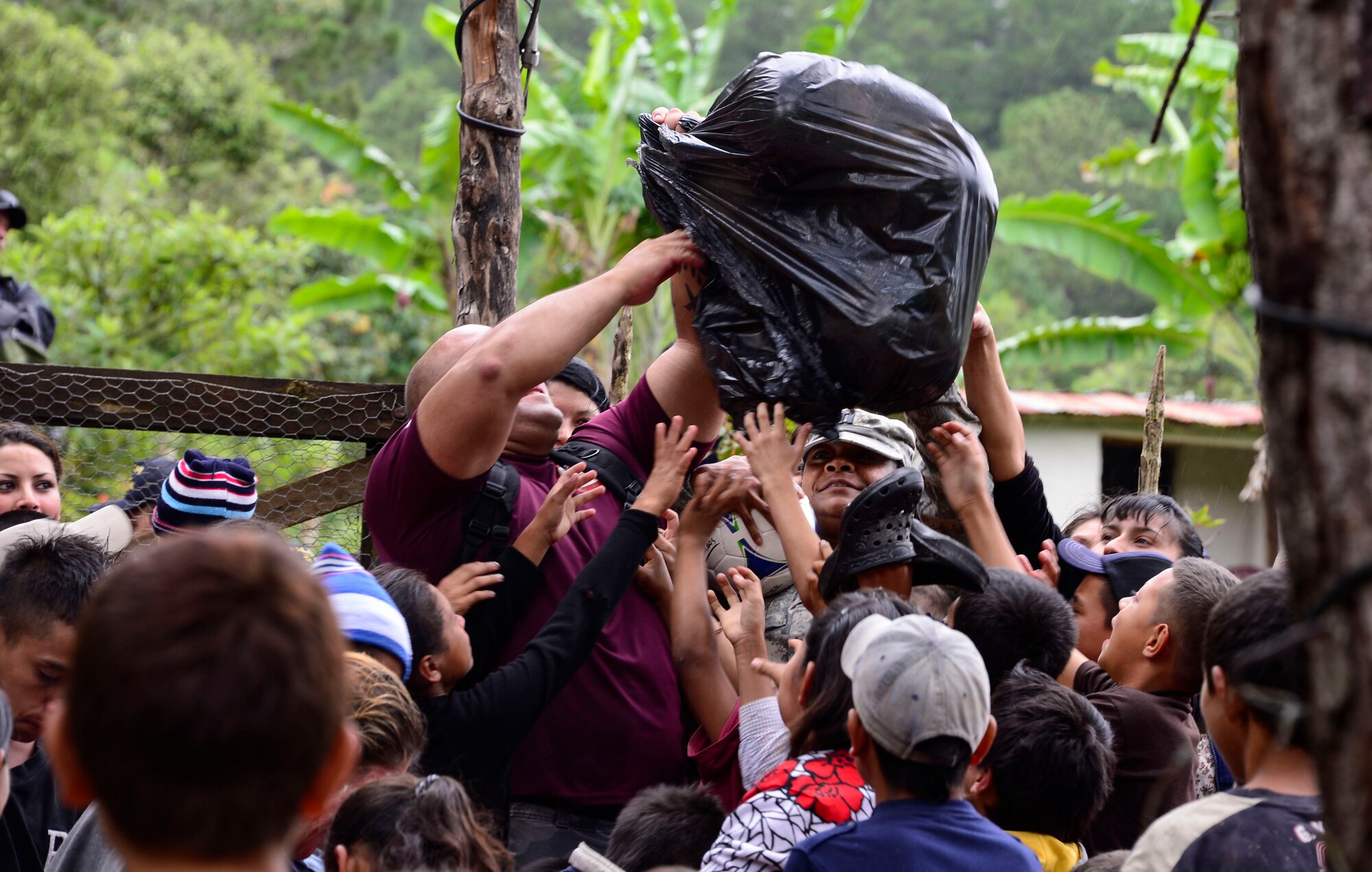 Volunteers from Joint Task Force-Bravo try to maintain order while handing out soccer balls to the children in Potrerillos, Siguatepeque, Honduras, Oct. 25, 2014.  The soccer balls were donated by the non-profit organization Kick for Nick Foundation.  As part of the 57th Chapel Hike, over 130 members assigned to Joint Task Force-Bravo laced up their hiking boots and trekked almost four miles up a mountain to help deliver over 3,500-pounds of donated dry goods to villagers in need. (U.S. Air Force photo/Tech. Sgt. Heather Redman)