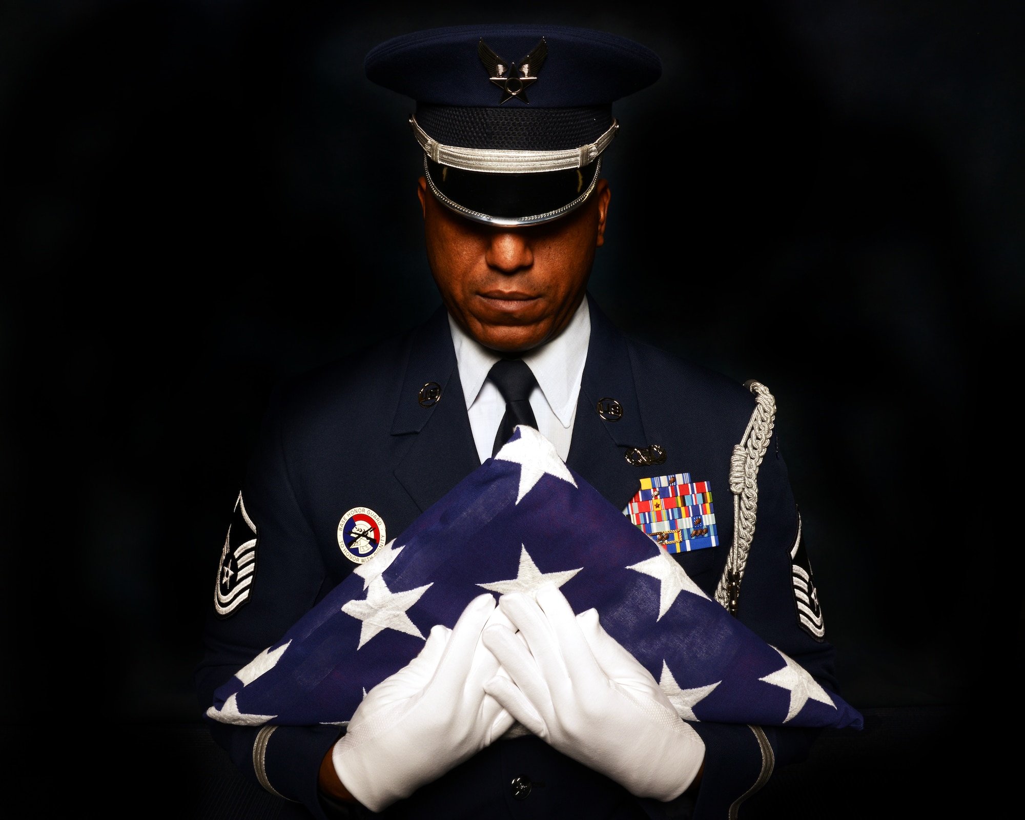 Master Sgt. Andre Moore, Aviano Base Honor Guard superintendent, clutches an American Flag to his chest during a studio portrait, Oct. 28, 2014, at Aviano Air base, Italy. Moore served with the U.S. Air Force Honor Guard for more than four years and uses his knowledge to develop Airmen at the Base Honor Guard level. (U.S .Air Force photo/Airman 1st Class Ryan Conroy) 