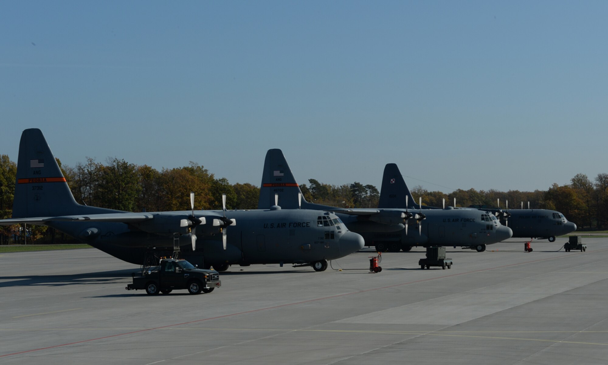 Two U.S. Air Force C-130 Hercules cargo aircraft assigned to the182nd Airlift Wing, Illinois Air National Guard, Peoria, Ill, and a Polish C-130E cargo aircraft sit on the flight line Oct. 24, 2014, at Powidz Air Base, Poland. Roughly 50 Airmen and three C-130s from the 182nd AW, participated in bilateral training with the Polish air force hosted by the U.S. Air Force Aviation Detachment 1, 52nd Operations Group, Lask Air Base, Poland. (U.S. Air Force photo by Airman 1st Class Dylan Nuckolls/Released)
