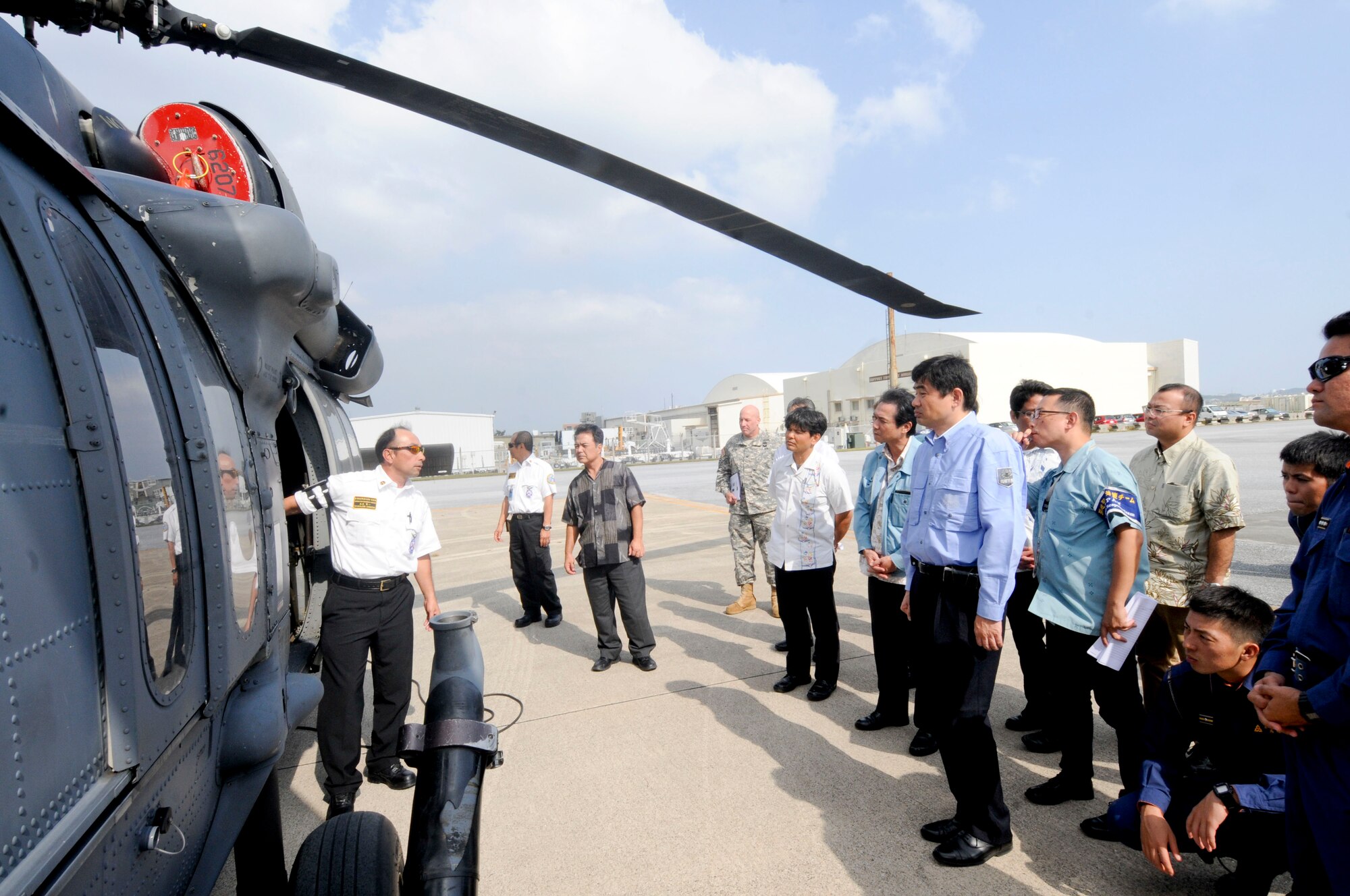 Kenichi Shimajiri, 18th Civil Engineering Squadron crew chief, explains the door functionality of an HH-60 helicopter during an annual bilateral aircraft mishap hands-on training on Kadena Air Base, Japan, Oct. 28, 2014. The purpose of this training is to enhance Japanese firefighters' skills in responding to an aircraft fire and as well as to enhance bilateral first responder cooperation. (U.S. Air Force photo by Tech. Sgt. Darnell T. Cannady/Released)