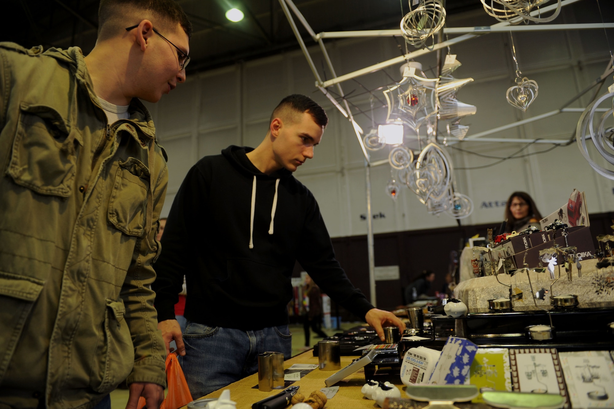 U.S. Air Force Airman 1st Class Antonio Villalobos from Phelan, Calif., left, and U.S. Air Force Airman 1st Class Matthew Hooks from Inverness, Fla., both 52nd Equipment Maintenance Squadron aerospace ground equipment journeymen, shop at a vendor’s stand during the 2014 Holiday Bazaar in Hangar 1 at Spangdahlem Air Base, Germany, Oct. 25, 2014. The bazaar allowed Spangdahlem Airmen and their families to interact with vendors from the local community and around Europe. (U.S. Air Force photo by Airman 1st Class Timothy Kim/Released)