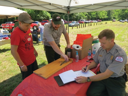 Park Ranger Michael Rakes (center) and Jay Davis measure the fish caught by a contestant at East Lynn’s tournament for kids.