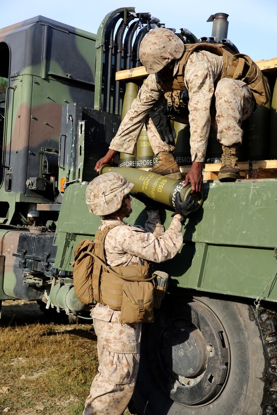 Lance Cpl. Vicki A. Harris, left, a cannoneer with Battery A, Ground Combat Element Integrated Task Force, receives an M777A2 Lightweight Howitzer round for the Gun 3 ammo pit prior to conducting live-fire artillery missions at Marine Corps Base Camp Lejeune, North Carolina, Oct. 30, 2014. Marines of Battery A conducted a live-fire artillery shoot, Oct. 28-30, 2014. From October 2014 to July 2015, the GCEITF will conduct individual and collective level skills training in designated ground combat arms occupational specialties in order to facilitate the standards based assessment of the physical performance of Marines in a simulated operating environment performing specific ground combat arms tasks. (U.S. Marine Corps photo by Sgt. Alicia R. Leaders/Released)
