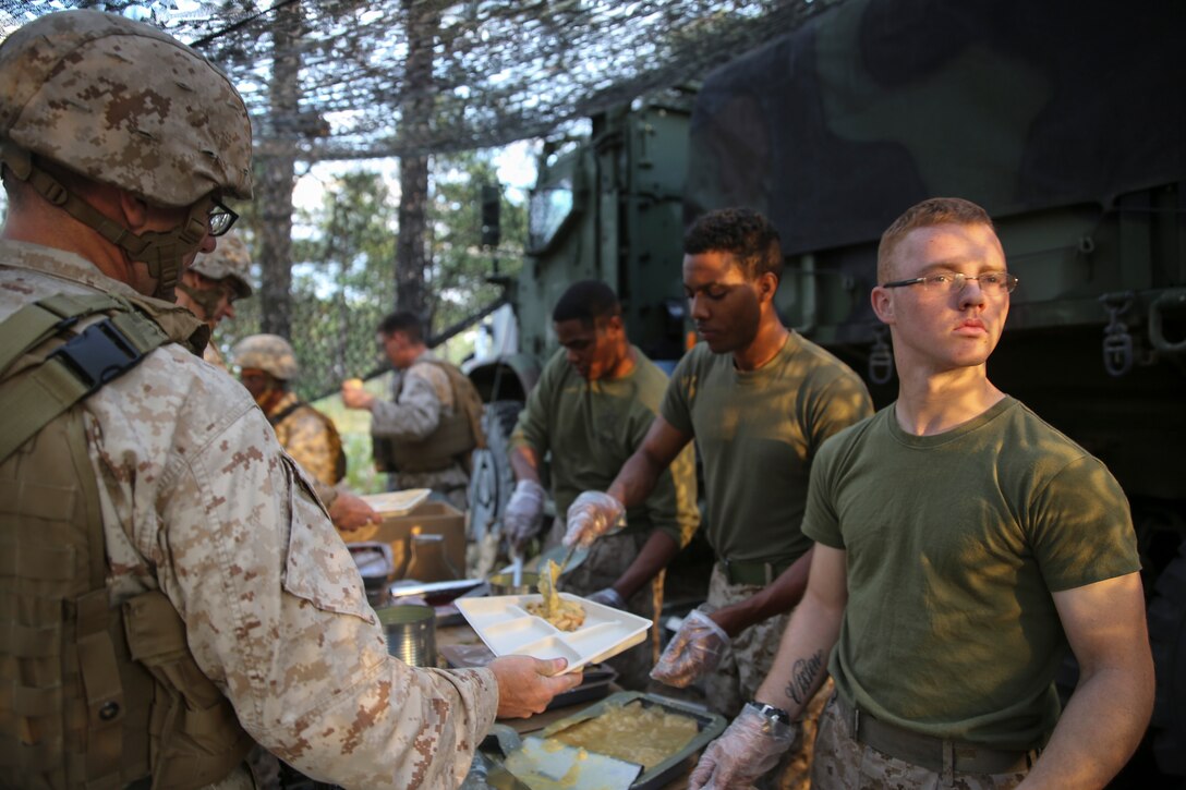 Food service specialists with 10th Marine Regiment, 2nd Marine Division,  serve a warm meal to Marines during Exercise Rolling Thunder on Fort Bragg, N.C., Oct. 21, 2014.  “It’s nice to eat something warm that you don’t have to open out of a package while you’re in the field.  Marines definitely appreciate the chance to talk about their day over a hot meal,” said Gunnery Sgt. Stanley Clink, a watch chief for Headquarters Battery, 10th Marines, and a Sweetwater, Tenn., native. Rolling Thunder tested the Marines’ ability to work together as a Marine Air-Ground Task Force. The food service specialists did their part by boosting morale by with hot meals in a deployed environment. (U.S. Marine Corps photo by Lance Cpl. Kirstin Merrimarahajara/Released)