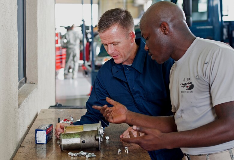 Airman 1st Class Alex Phifer, 8th Logistics Readiness Squadron vehicle maintenance technician, prepares to install a starter on a vehicle with Col. Ken “Wolf” Ekman, 8th Fighter Wing commander at Kunsan Air Base, Republic of Korea, Sept. 5, 2014.  Phifer was recognized by the 8th LRS as one of their outstanding performers. (U.S. Air Force photo by Senior Airman Divine Cox)