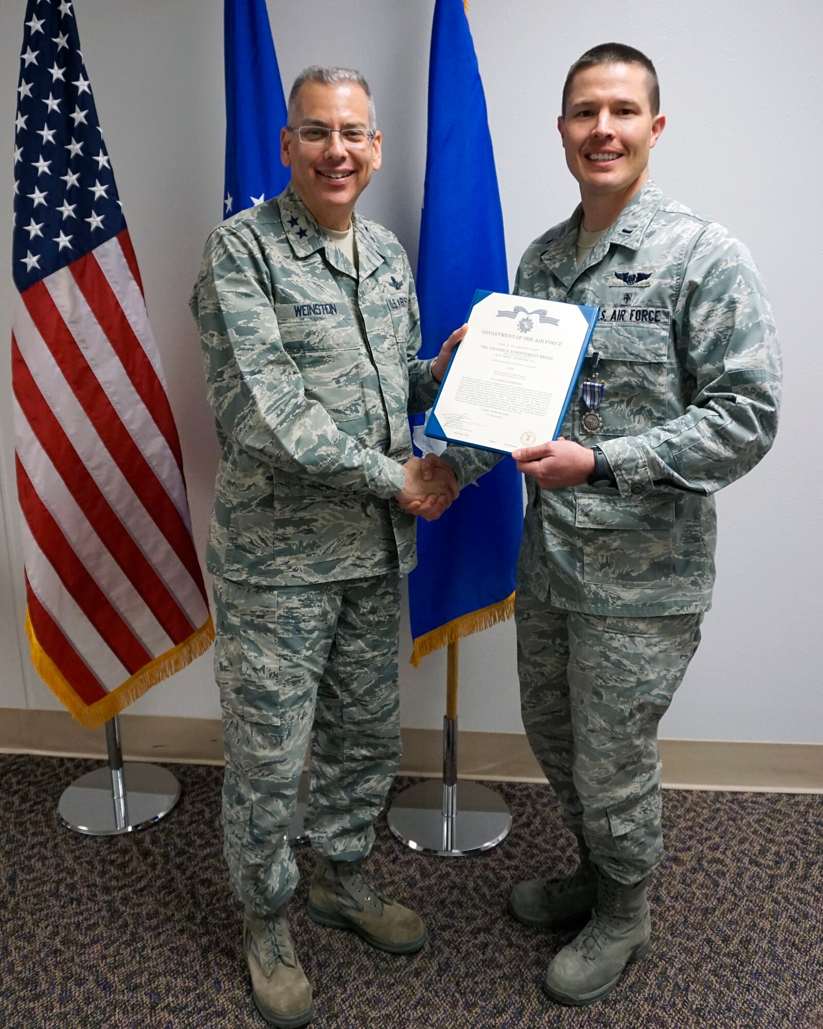 Maj. Gen. Jack Weinstein, Task Force 214 and 20th Air Force commander, presents the Air Force Achievement Medal to 1st Lt. Klinton Holscher, 90th Medical Support Squadron Oct. 28, 2014, on F.E. Warren Air Force Base, Wyo. The AFAM was awarded to Holscher for his role in implementing a newly created flight commander's course. (U.S. Air Force photo by Lan Kim)
