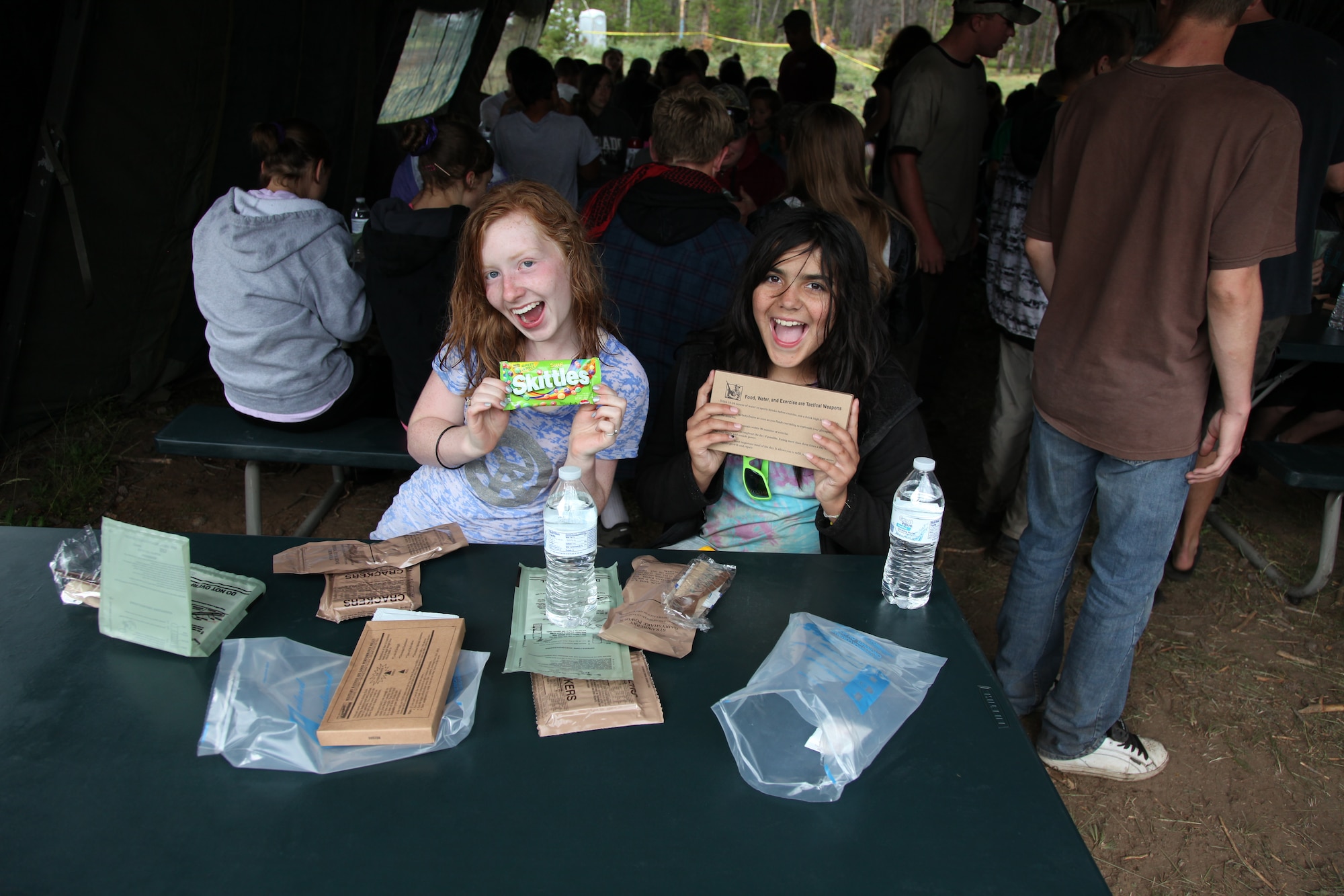 A couple of teenage girls enjoy trying an MRE (Meal Ready to Eat) during the week-long Laramie River Valley Rendezvous program near Ft. Collins, Colo. The kids, who are identified as being high-risk for potential drug use, participate in various games and activities throughout the week and are mentored by members of the Colorado National Guard. (U.S. Air National Guard Photo by Tech. Sgt. B. Kevin Coulter) 