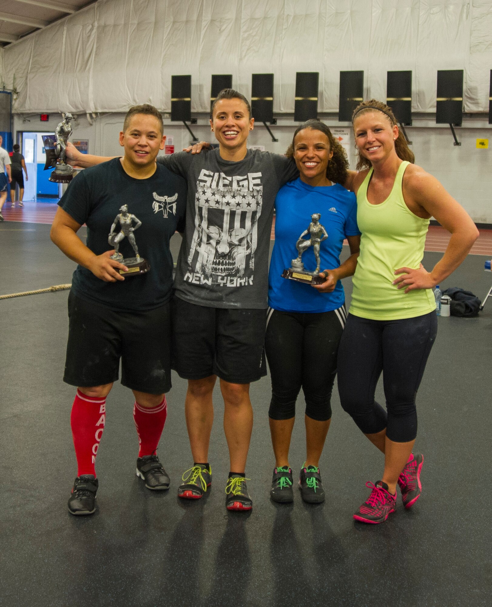 The four women competitors of the 2nd Annual Premier Strongman Challenge pose for a photo after the event at the West Fitness Center on Joint Base Andrews, Md., Oct. 28, 2014. They competed in a tire flip and sled-pull medley, a farmer’s walk, deadlifts, and a log and clean press. (U.S. Air Force photo/Airman 1st Class Ryan J. Sonnier)