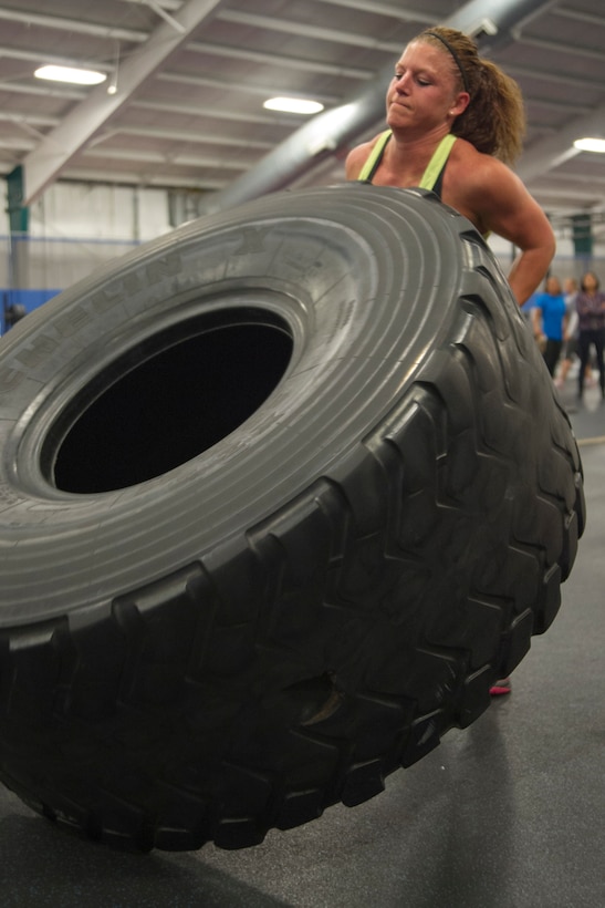 Staff Sgt. Lynn Handle, a 1st Airlift Squadron flight attendant, flips a 450-pound tire during the 2nd Annual Premier Strongman Challenge at the West Fitness Center on Joint Base Andrews, Md., Oct. 28, 2014. Handle was one of four women to compete in the challenge. (U.S. Air Force photo/Airman 1st Class Ryan J. Sonnier)