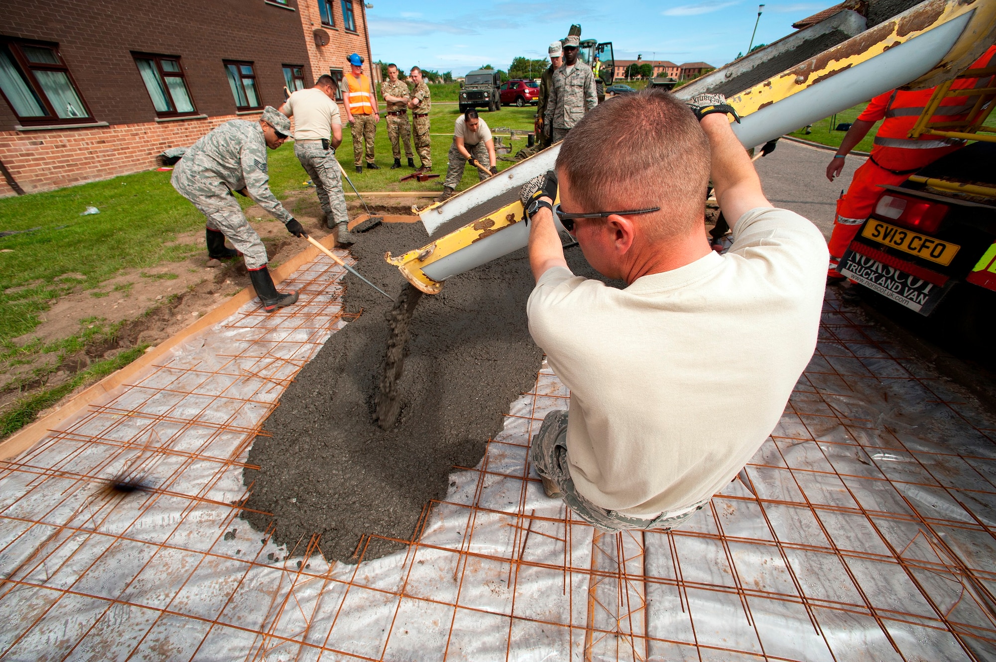 U.S. Air Force Master Sgt. Adam Elliott, 140th Civil Engineer Squadron, Colorado Air National Guard, guides fresh cement into a large space that will help to improve the base junior dorms area once completed, during a deployed for training trip, known as Exercise Flying Rose at Kinloss Barrack in Forres, Moray, Scotland, United Kingdom, Jun. 16, 2014. Over 40 members of the 140th CES are in Scotland for their annual training and are accomplishing five construction projects that will improve several areas around Kinloss Barracks, during Exercise Flying Rose hosted by the British Army before returning back to Colorado later this month. (U.S. Air National Guard photo byTech. Sgt. Wolfram M. Stumpf)