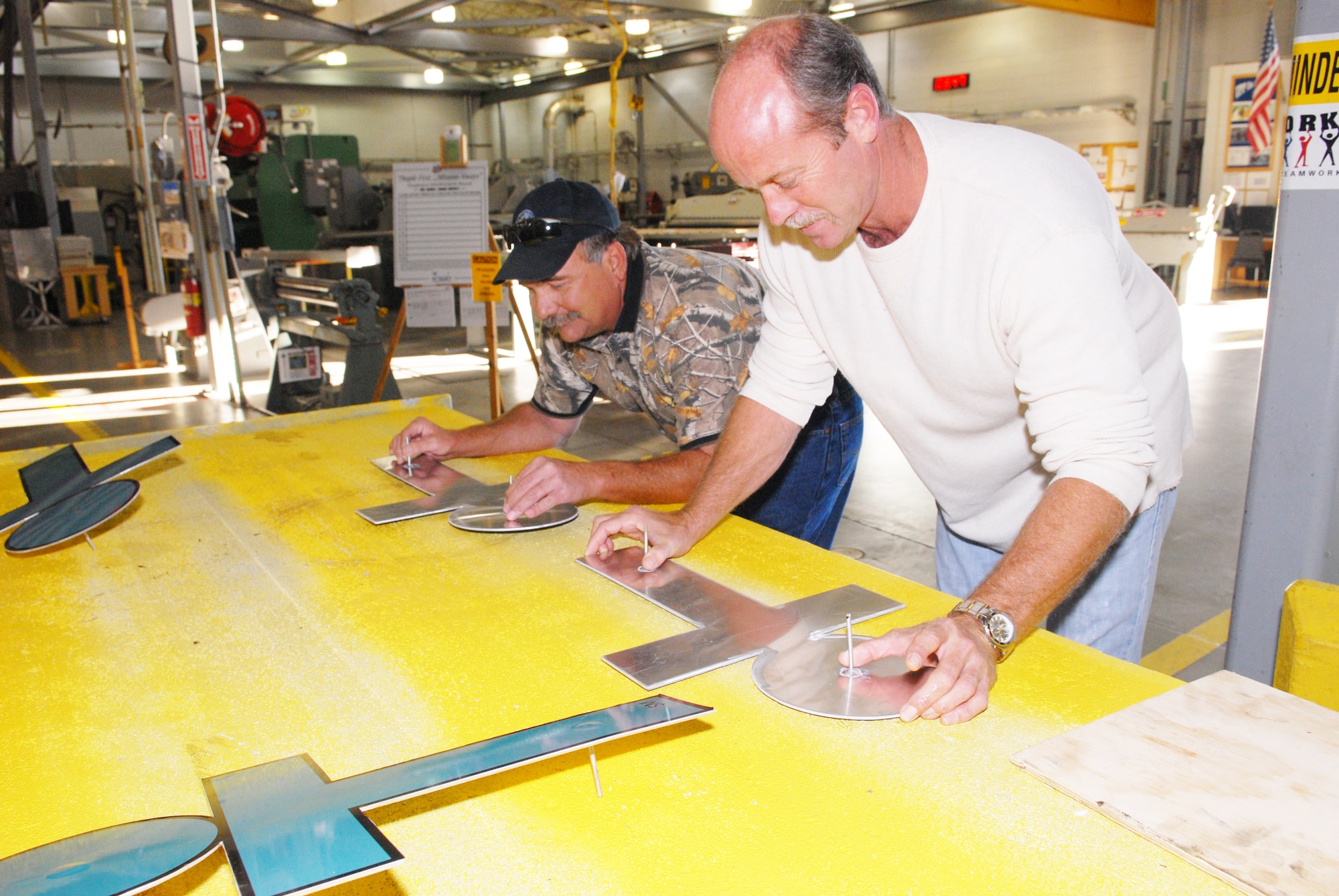 Bruce Scott and Eddie Greene, 402nd Aircraft Maintenance Support Squadron, attach “iT” graphics to metal signs Oct. 16. The signs are now displayed at the gates.  U.S. Air Force photo by Mizuzu Allen
