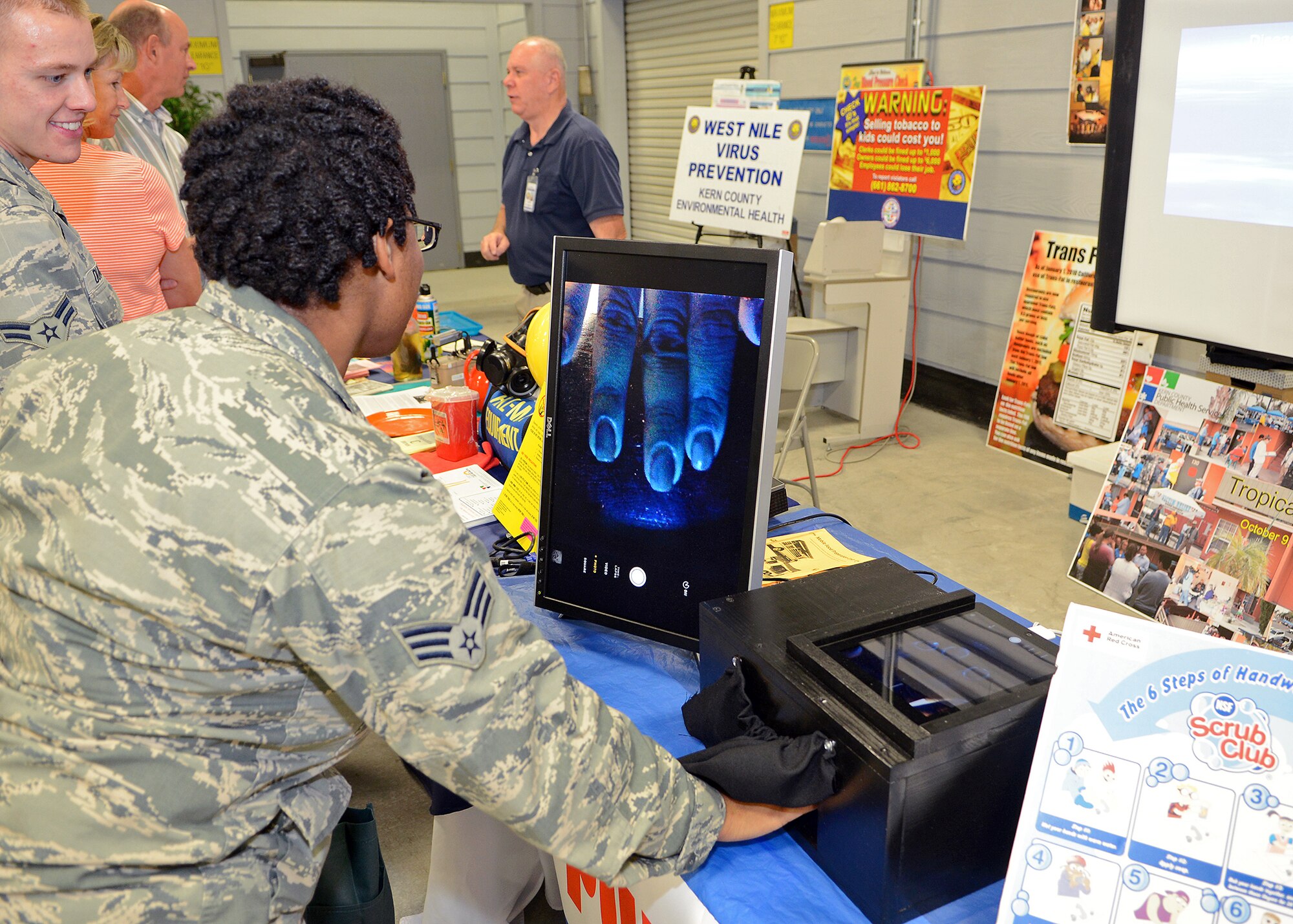 Senior Airman Dominique Lyles, 412th Medical Group medical technician, places her hand under the glow germ demonstration at the Kern County Environmental Health Division booth during the 412th MDG Health Fair held Oct. 23 at Bldg. 1600. Participants were asked to place lotion and talcum powder while having them attempt to properly wash their hands and to see what places they missed. The health fair offered free health information on a variety of health topics including high cholesterol, back pain relief, weight loss, high blood pressure and screening tools for skin, breast and prostate cancer. (U.S. Air Force photo by Jet Fabara)