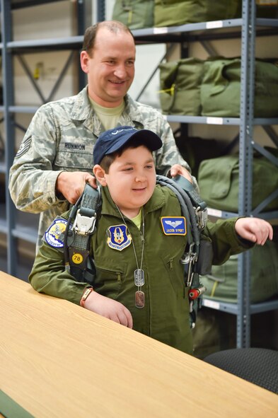 U.S. Air Force Reserve Tech. Sgt. Charles Runnion, an aircrew flight equipment craftsman with the 910th Operations Support Squadron, helps 11-year-old Jacob Sypert, the 910th Airlift Wing’s 60th Pilot for a Daytry on a parachute here, Oct. 29, 2014. Sypert was sworn in as an honorary second lieutenant and spent the day here experiencing military activities including a high-speed taxi down the runway in a Youngstown C-130H Hercules aircraft. The Pilot for a Day program began in 2000 as a community outreach event for the purpose of providing a fun-filled day for children with life-threatening or chronic illnesses. U.S. Air Force photo/Eric M. White
