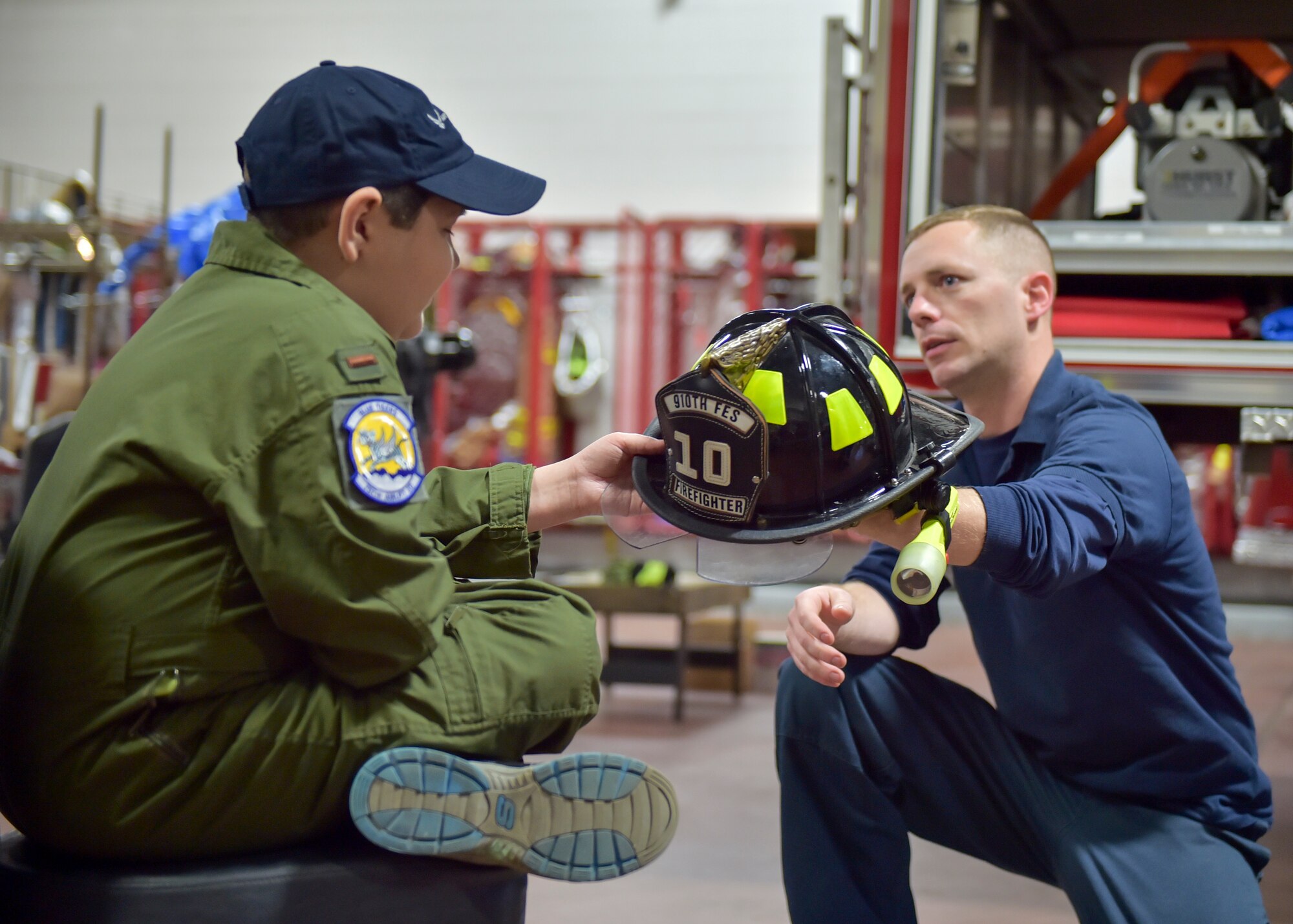 Tim Wertz, a firefighter with the 910th Civil Engineer Fire Department, shows a fire helmet to 11-year-old Jacob Sypert here, Oct. 29, 2014. Sypert became the 910th Airlift Wing’s 60th Pilot for a Day, being sworn in as an honorary second lieutenant and spending the day here experiencing military activities including a high-speed taxi down the runway in a Youngstown C-130H Hercules aircraft. The Pilot for a Day program began in 2000 as a community outreach event for the purpose of providing a fun-filled day for children with life-threatening or chronic illnesses. U.S. Air Force photo/Eric M. White