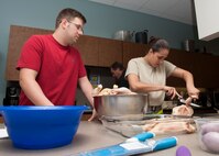First Lt. James Aultman, 436th Mission Support Group executive officer, and Senior Airman Dominique Pascual, 436th Aerial Port Squadron cargo processor, debone raw chickens during a “Dorm to Gourm” Leadership Pathways Professional Development course Oct. 28, 2014, at the fitness center on Dover Air Force Base, Del.  Course instructors taught the Airmen how to make a “not your momma’s chicken and dumplings” dish. (U.S. Airman 1st Class Zachary Cacicia)