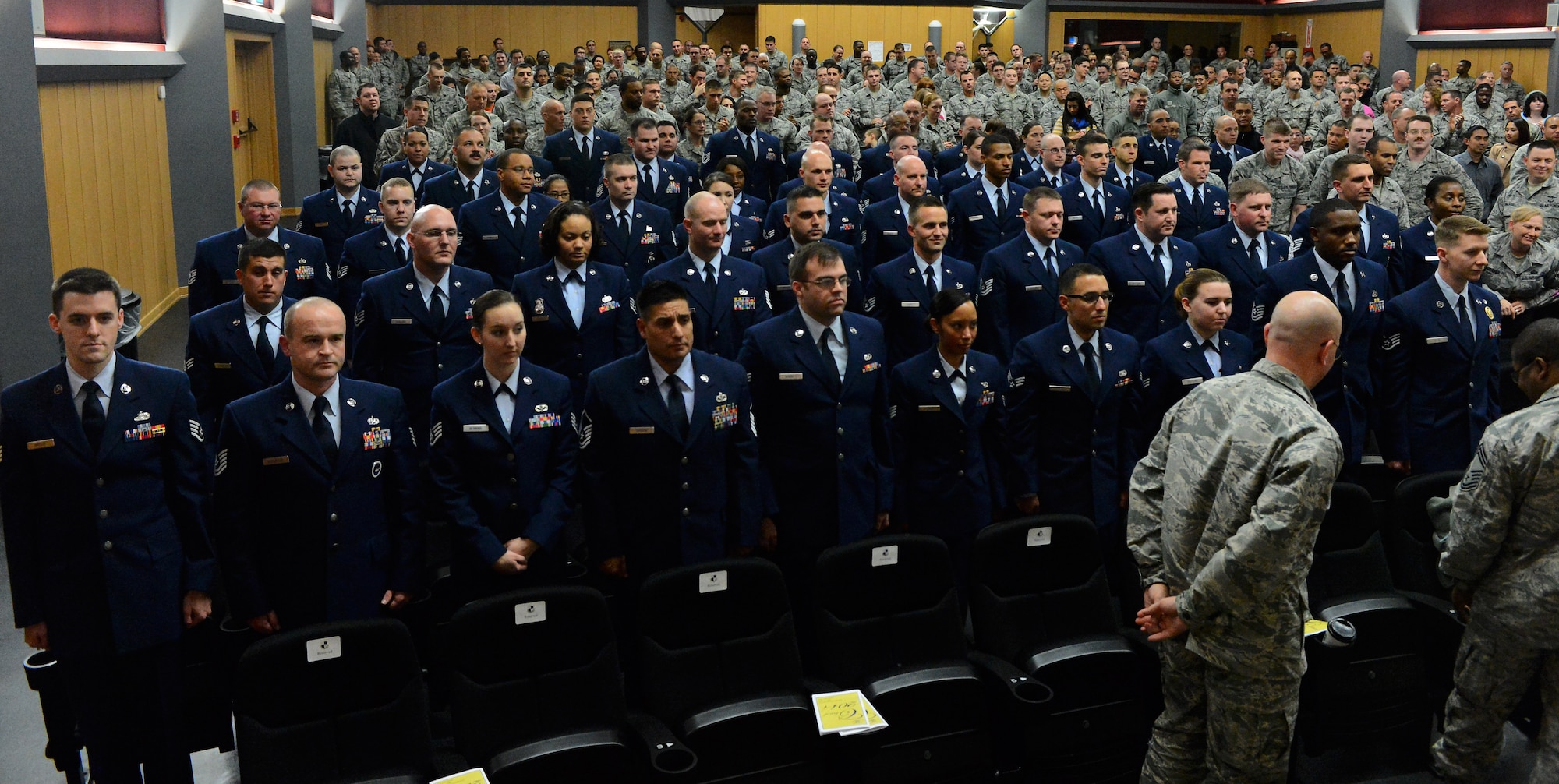 Community College of the Air Force graduates stand as they receive applause from family, friends and co-workers during a graduation ceremony at the base theater on Spangdahlem Air Base, Germany, Oct. 29, 2014. More than 60 Airmen received their CCAF diplomas in various degrees ranging from dental assistant to fire science. (U.S. Air Force photo by Airman 1st Class Luke Kitterman/Released)