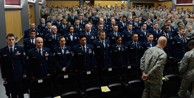 Community College of the Air Force graduates stand as they receive applause from family, friends and co-workers during a graduation ceremony at the base theater on Spangdahlem Air Base, Germany, Oct. 29, 2014. More than 60 Airmen received their CCAF diplomas in various degrees ranging from dental assistant to fire science. (U.S. Air Force photo by Airman 1st Class Luke Kitterman/Released)