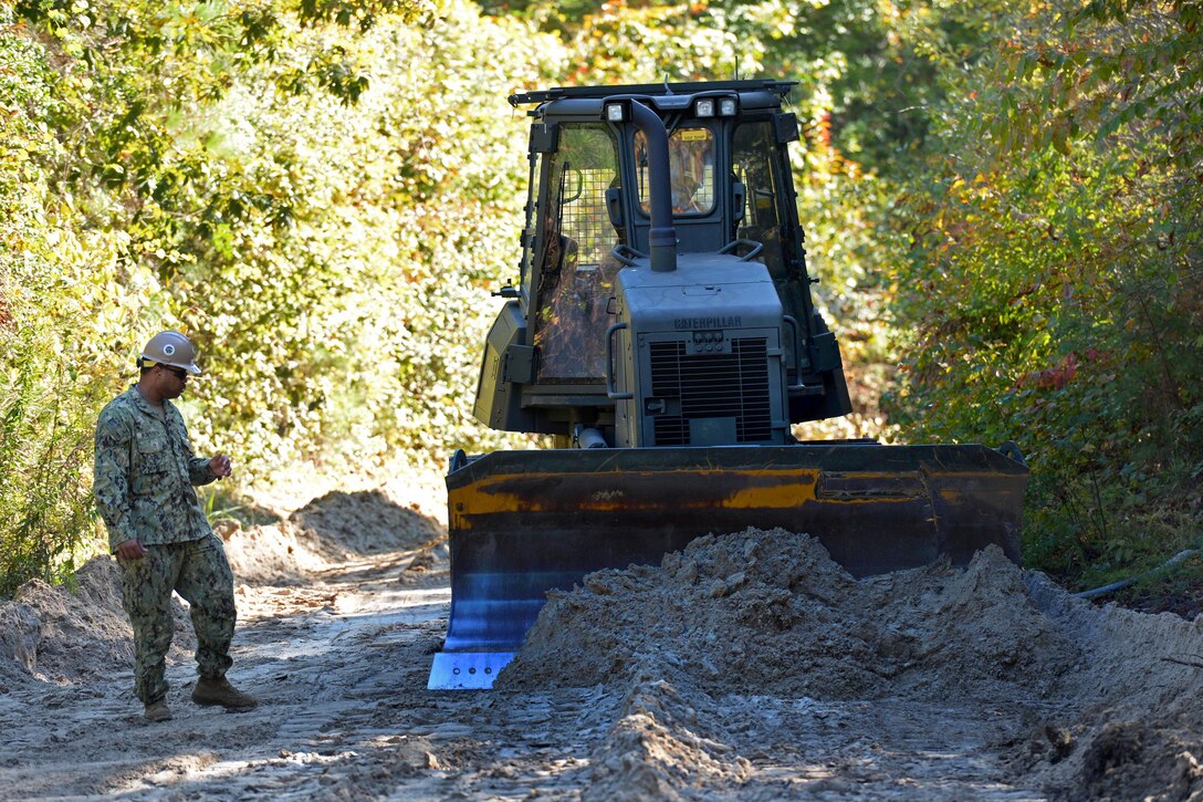 Navy Petty Officer Travis Morrison guides a Caterpillar D6 bulldozer for a road improvement project on Marine Corps Air Station New River, Jacksonville, N.C., Oct. 28, 2014. Morrison is an equipment operator assigned to Naval Mobile Construction Battalion 1.