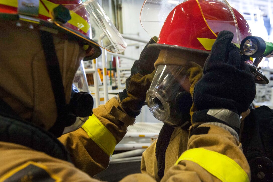 Navy Seaman Devan Mcneilly, left, checks over the firefighting gear of Navy Petty Officer 2nd Class Zachary Turner during a general quarters drill aboard the aircraft carrier USS John C. Stennis in Bremerton, Wash., Oct. 27, 2014. Mcneilly is a hose team leader and aviation ordnanceman, and Turner is an aviation electronics technician.