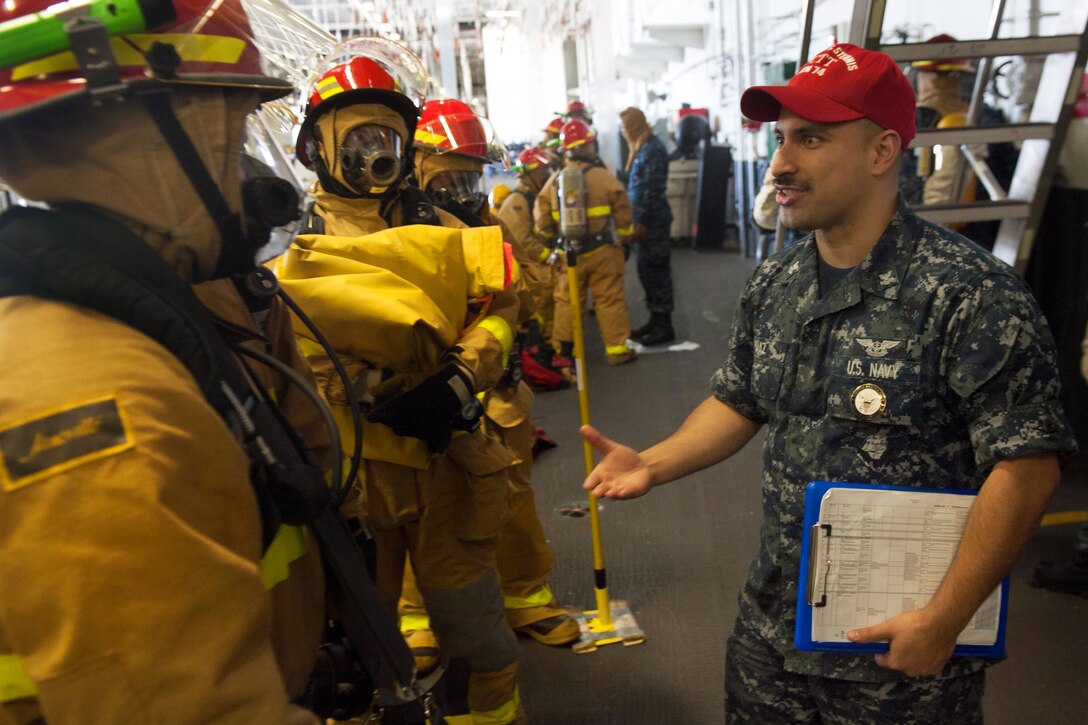 Navy Petty 2nd Class Luis Diaz, right, briefs hose team members during a general quarters drill aboard the aircraft carrier USS John C. Stennis in Bremerton, Wash., Oct. 27, 2014. Diaz is a damage control training team member. The Stennis is undergoing a docking planned incremental availability maintenance period at Puget Sound Naval Shipyard and Intermediate Maintenance Facility. 