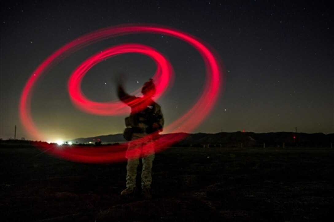 A Marine signals the landing zone for an MV-22B Osprey during a vertical assault raid exercise on Camp Pendleton, Calif., Oct. 27, 2014. The Marines are assigned to Lima Company, Battalion Landing Team 3rd Battalion, 1st Marine Regiment, 15th Marine Expeditionary Unit.