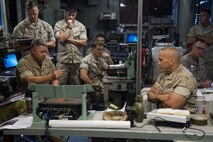 Maj. Gen. Richard L. Simcock, commanding general of the 2nd Marine Expeditionary Brigade, talks with Lt. Col. Wayne Waltrip, Force Effects Coordinator, and his staff aboard the USS Iwo Jima, Oct. 29, 2014. Simcock and Thebaud took command aboard the USS Iwo Jima within 24 hours notice by executing the experimental Fly-In and Integrated Command Element concept aboard the USS Iwo Jima off the coast of North Carolina. The FICE, part of the Marine's Expeditionary Force 21 Concept, is one of many experiments being conducted during Exercise Bold Alligator 2014.