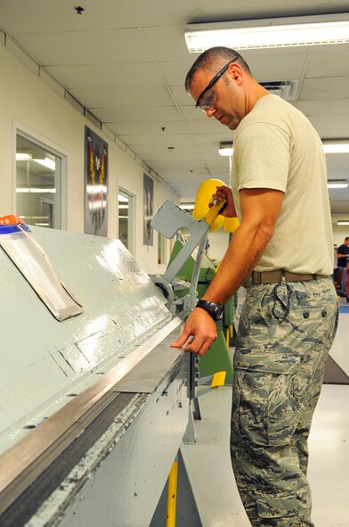 Staff Sgt. Jason Mayfield, 1st Special Operations Equipment Maintenance Squadron aircraft structural maintenance lead technician, bends sheet metal with a 90- degree grinder on Hurlburt Field, Fla., Oct. 29, 2014. The sheet metal, after it is molded and shaped correctly, will be used to make repairs on MC-130P Combat Shadow. (U.S. Air Force photo/Airman 1st Class Andrea Posey)