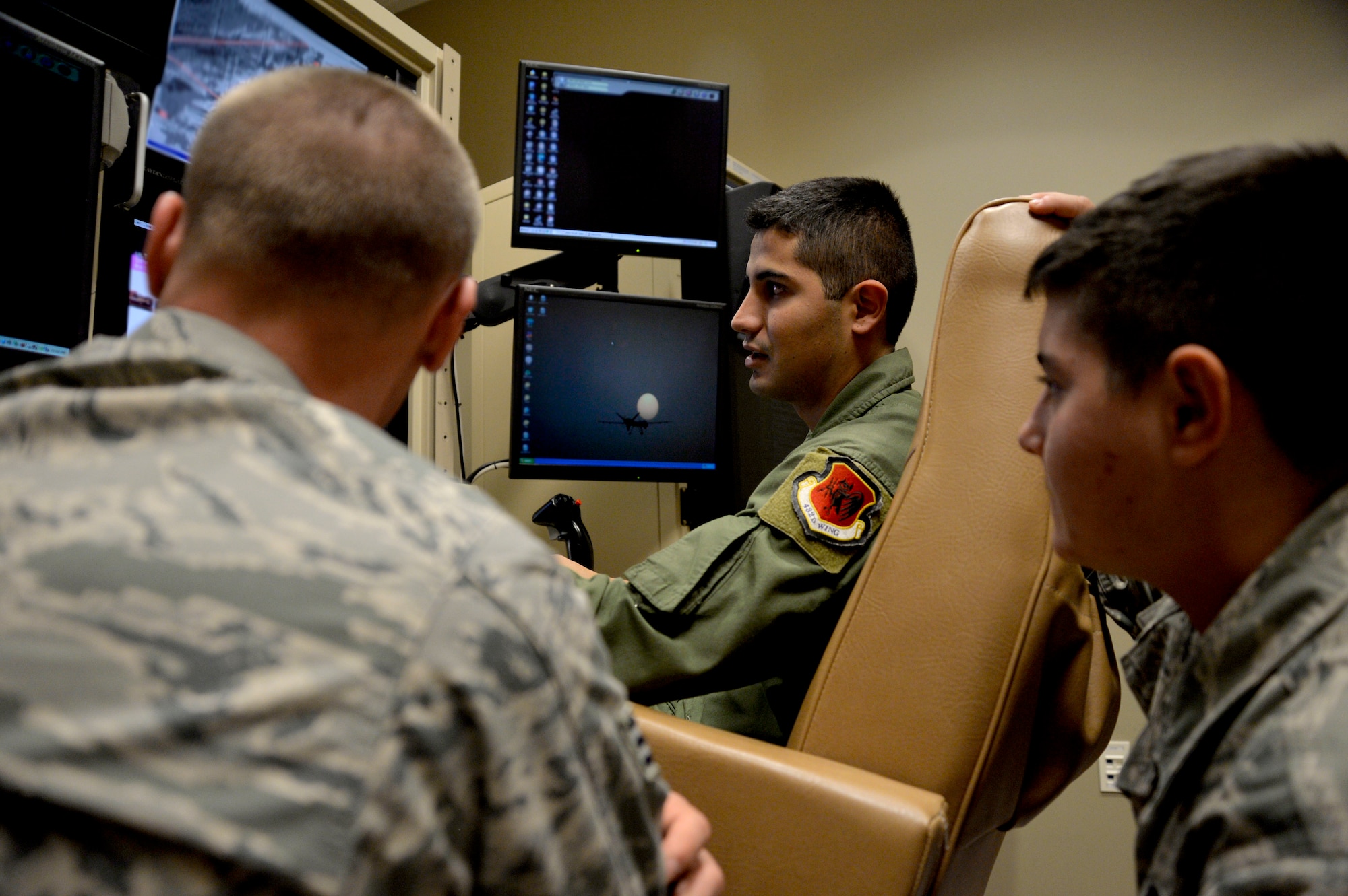 Senior Airman Maximiliano, 11th Reconnaissance Squadron sensor operator, center, gives a brief to Airman 1st Class Andy Borrino, 432nd Aircraft Maintenance Squadron Reaper weapons, right, and Senior Airman Zachary Heffner, 432nd AMXS Reaper avionics specialist, during integration training Oct. 24, 2014, at Creech Air Force Base, Nevada. The training covered various aspects of the pilot, sensor operator, and maintenance mission requirements to help build a better understanding between the operations and maintenance members. (U.S. Air Force photo by Staff Sgt. Adawn Kelsey/released some names have been withheld for security purposes)