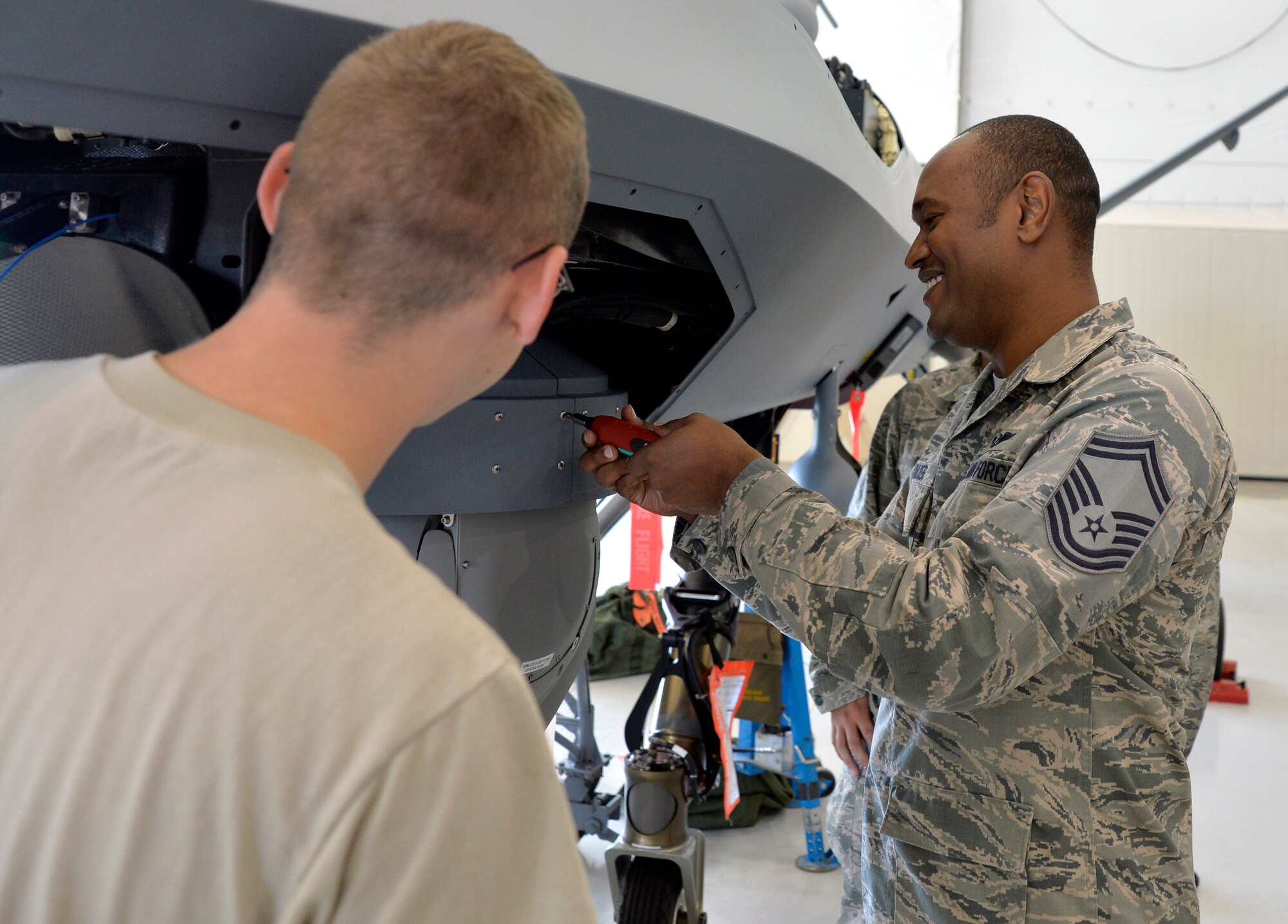 Senior Master Sgt. Roderick, 11th Reconnaissance Squadron squadron superintendent, tightens a bolt on the skirt of a Multi-spectral Targeting System ball on an MQ-9 Reaper during integration training Oct. 22, 2014, at Creech Air Force Base, Nevada. The integration training program was developed to help foster the relationship between the maintenance and operations squadrons on base. (U.S. Air Force photo by Staff Sgt. Adawn Kelsey/released some names have been withheld for security purposes)