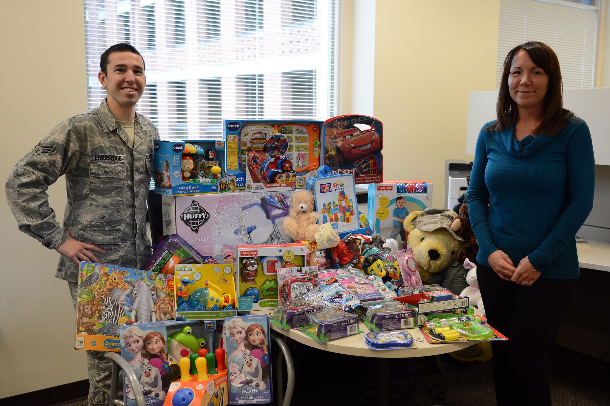 Senior Airman Robert Liversedge (left) and Stacy Crumpton (right), 627th Logistics Readiness Squadron personal property and passenger travel representatives, pose for a photo with donated toys for the Santa's Castle program, Oct. 30, 2014 at the McChord Field Traffic Management Office, Joint Base Lewis-McChord, Wash. The pair collected more than 60 brand new toys within a short two-week period to donate to the Santa's Castle program, a program designed to assist service members in need during the holidays (U.S. Air Force photo/Airman 1st Class Keoni Chavarria)