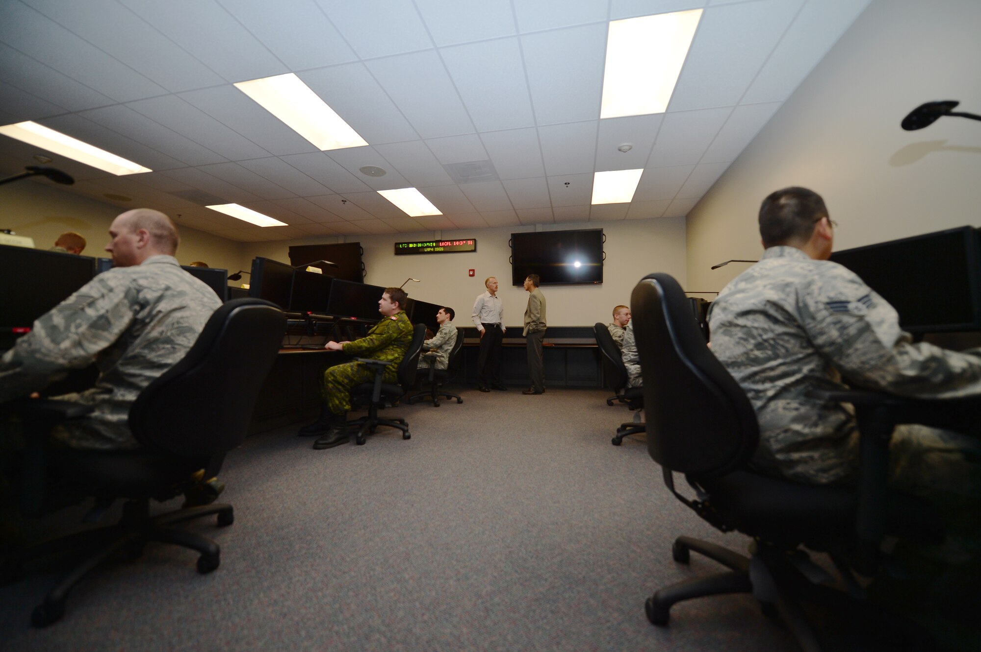 After completing a missile warning demonstration, members from the 460th Operations Group sit at their workstations in the new standardized space trainer Oct. 29, 2014, on Buckley Air Force Base, Colo. The new SST, which is one of two on base, houses 12 workstations and is designed to streamline the training process for 460th Space Wing space operators. (U.S. Air Force photo by Senior Airman Darren Scott/Released)