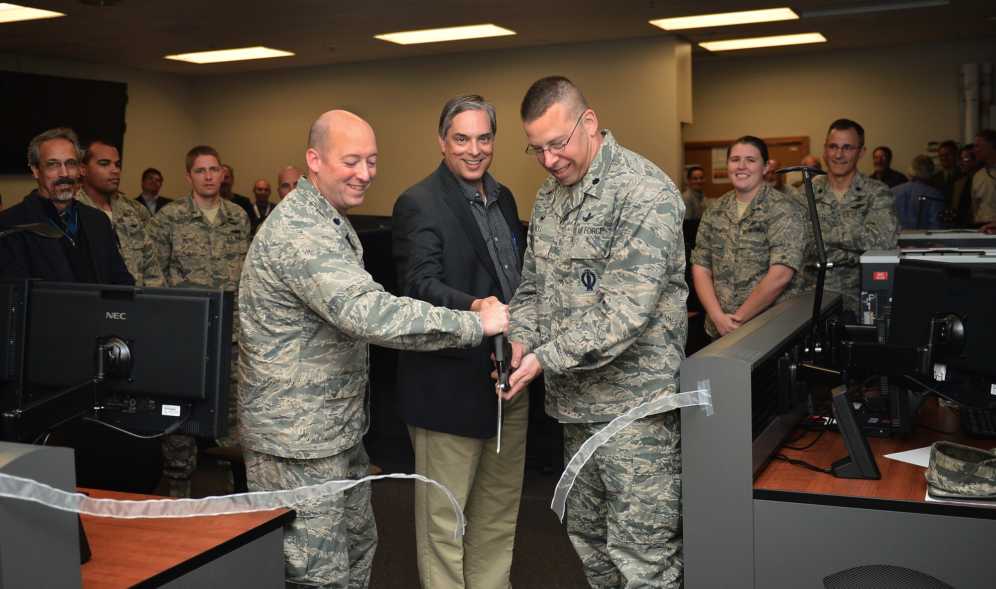 From left, Lt. Col. John Mizell, Space and Missile Systems Center material leader, Jeff Drake, Lockheed Martin Block 10 program manager, and Lt. Col. Timothy Bos, 460th Operations Support Squadron commander, cut a ribbon during the unveiling of a new standardized space trainer Oct. 29, 2014, on Buckley Air Force Base, Colo. The new SST houses 12 workstations and is designed to streamline the training process for 460th Space Wing space operators. (U.S. Air Force photo by Senior Airman Darren Scott/Released)