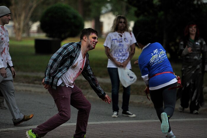 Runners try to avoid a zombie during the Joint Base Charleston Combined Federal Campaign Zombie Run Oct. 31, 2014, at JB Charleston, S.C. The 1.7 mile run forced runners to dodge zombies in three "contaminated" areas in order to "survive." (U.S. Air Force photo/Staff Sgt. Renae Pittman)