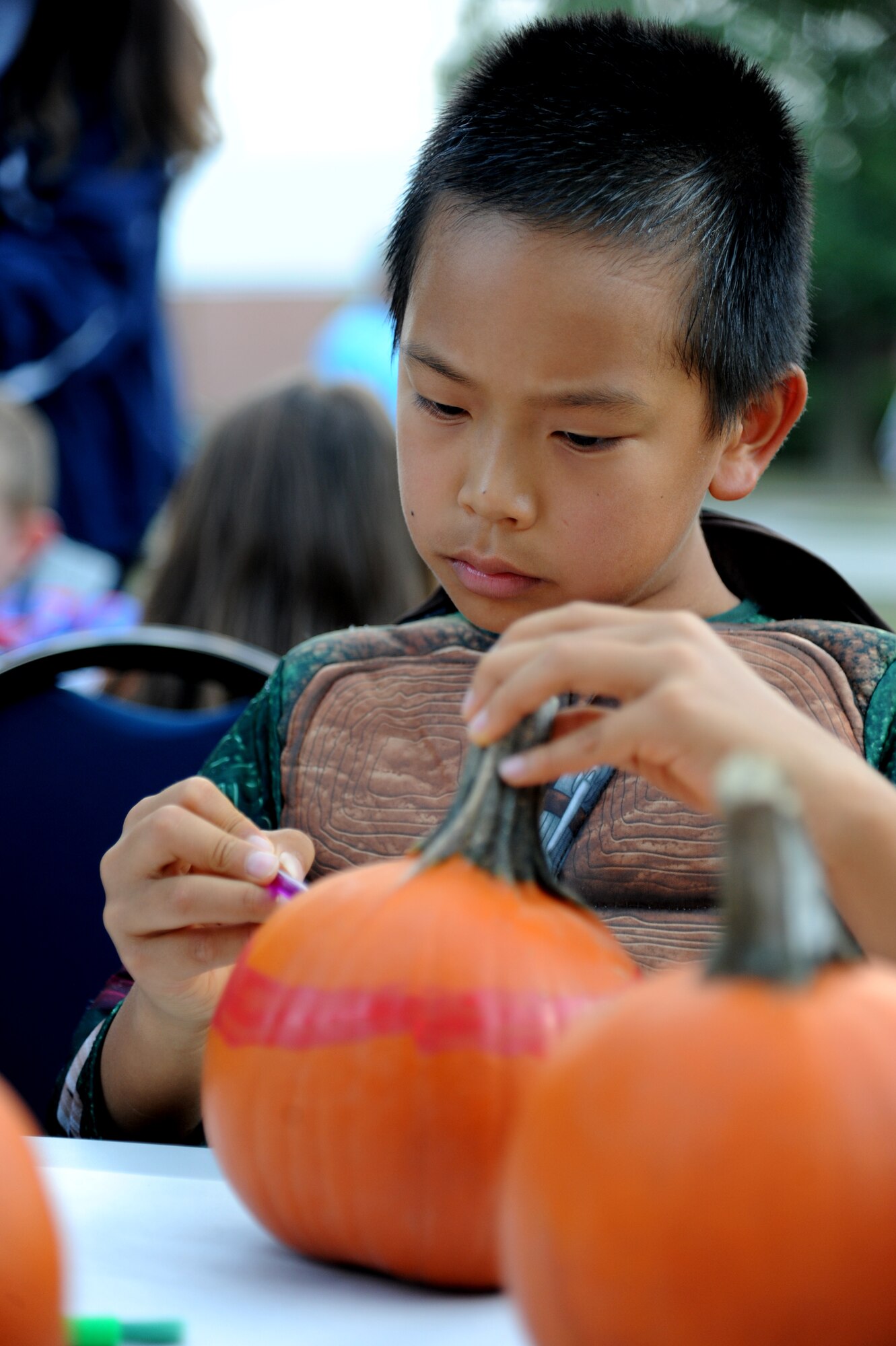 The son of Staff Sgt. Kevin Mendoza, 85th Engineering Installation Squadron, paints a pumpkin during the 2nd Annual 85th EIS Trunk-Or-Treat Oct. 29, 2014, at Maltby Hall, Keesler Air Force Base, Miss.  The event also included a costume contest and trunk-or-treating.  (U.S. Air Force photo by Kemberly Groue)
