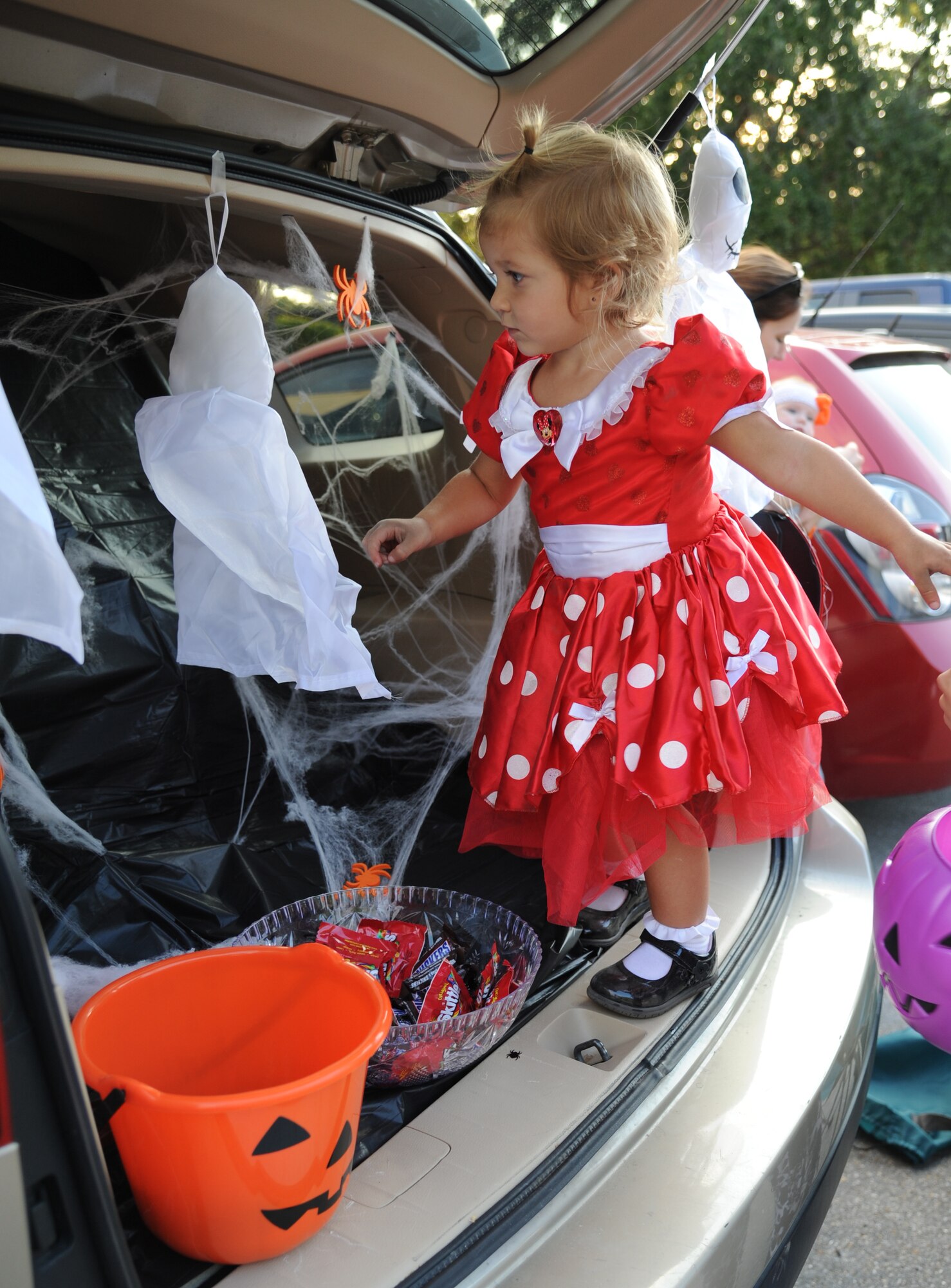 The daughter of Capt. Tomasz Krygowski, 85th Engineering Installation Squadron, stands in the trunk of a vehicle to get candy during the 2nd Annual 85th EIS Trunk-Or-Treat Oct. 29, 2014, at Maltby Hall, Keesler Air Force Base, Miss.  The event included a costume contest, trunk-or-treating and pumpkin painting. (U.S. Air Force photo by Kemberly Groue)